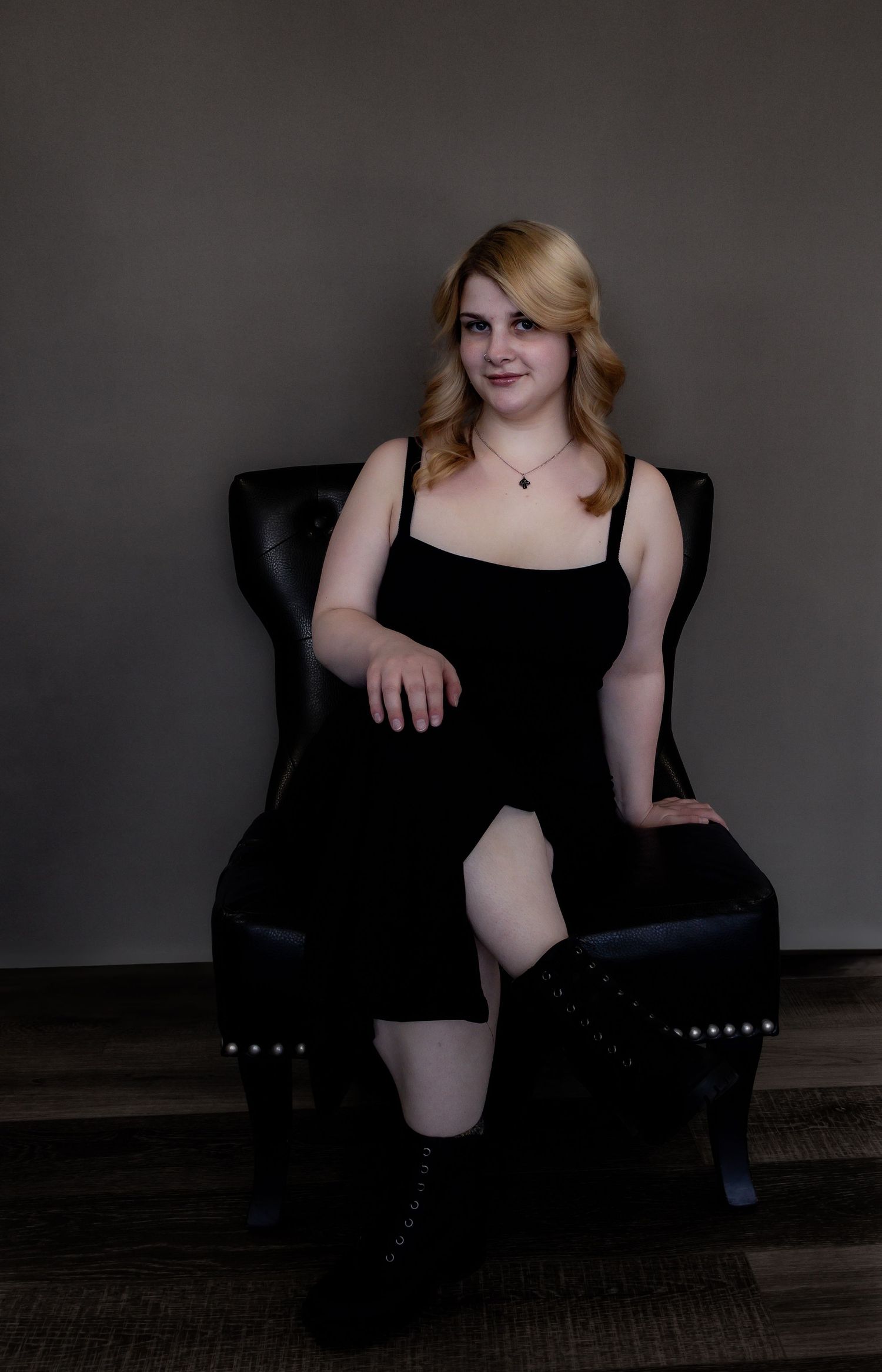 Dramatic portrait series in black attire against dark background showing relaxed poses in a chair.