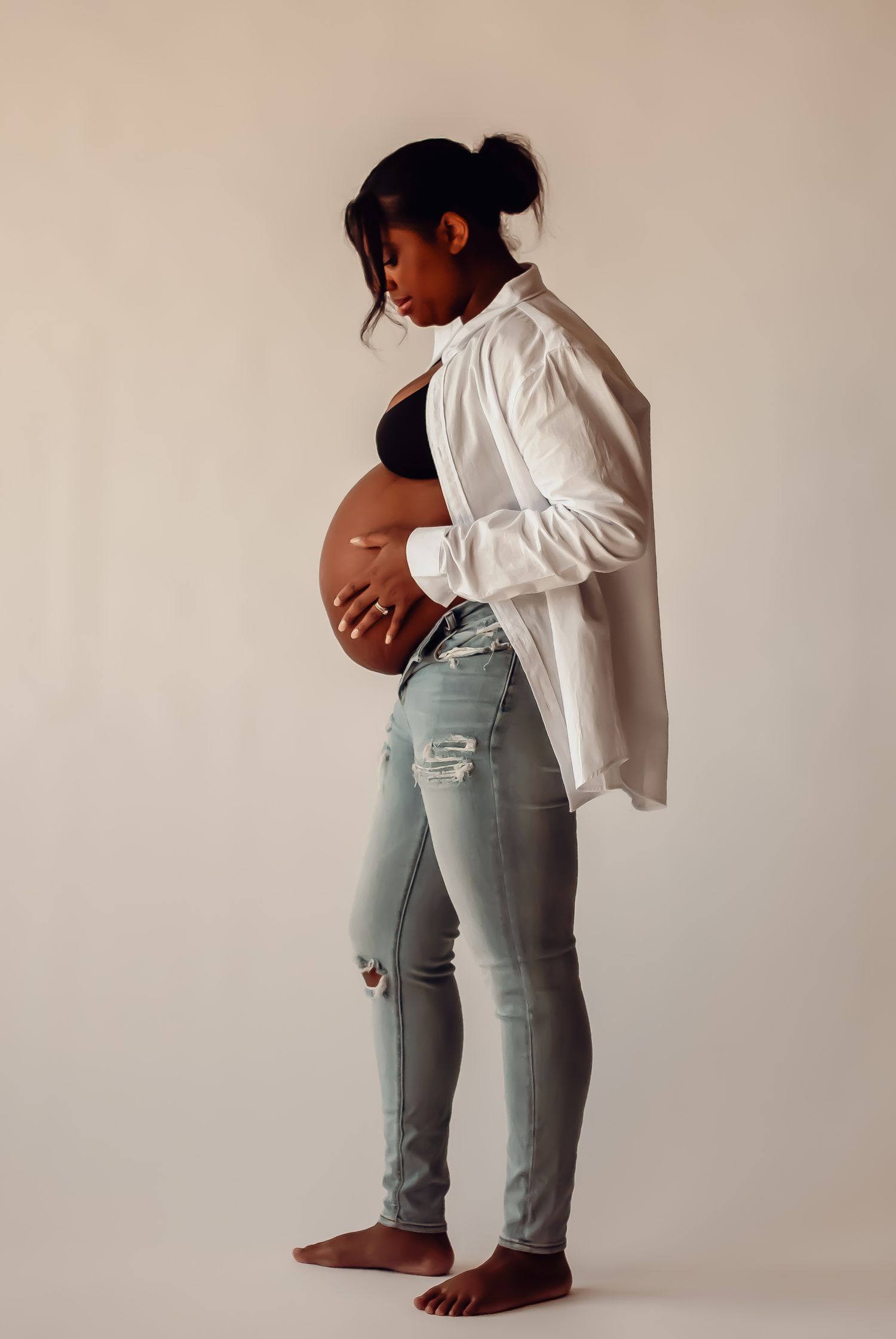 A person in light jeans and white shirt sits on a stool against a white backdrop in a minimalist photo series.