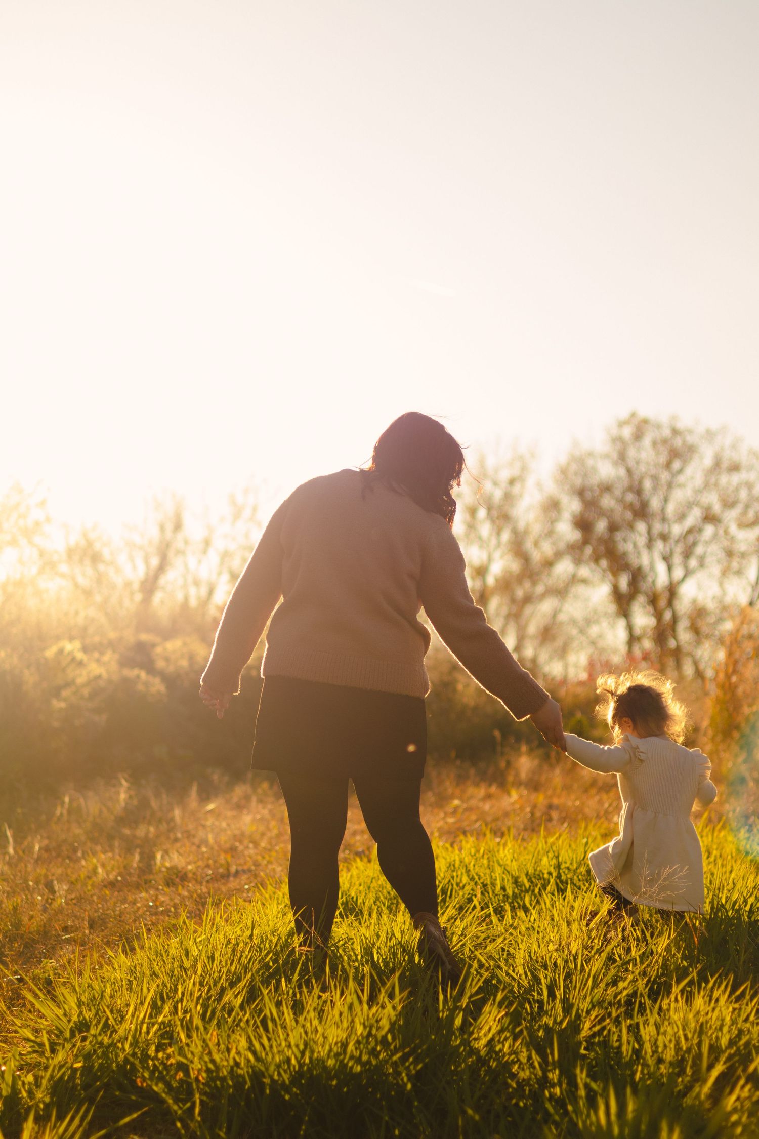 Silhouettes playing in a grassy field during golden sunset hour.