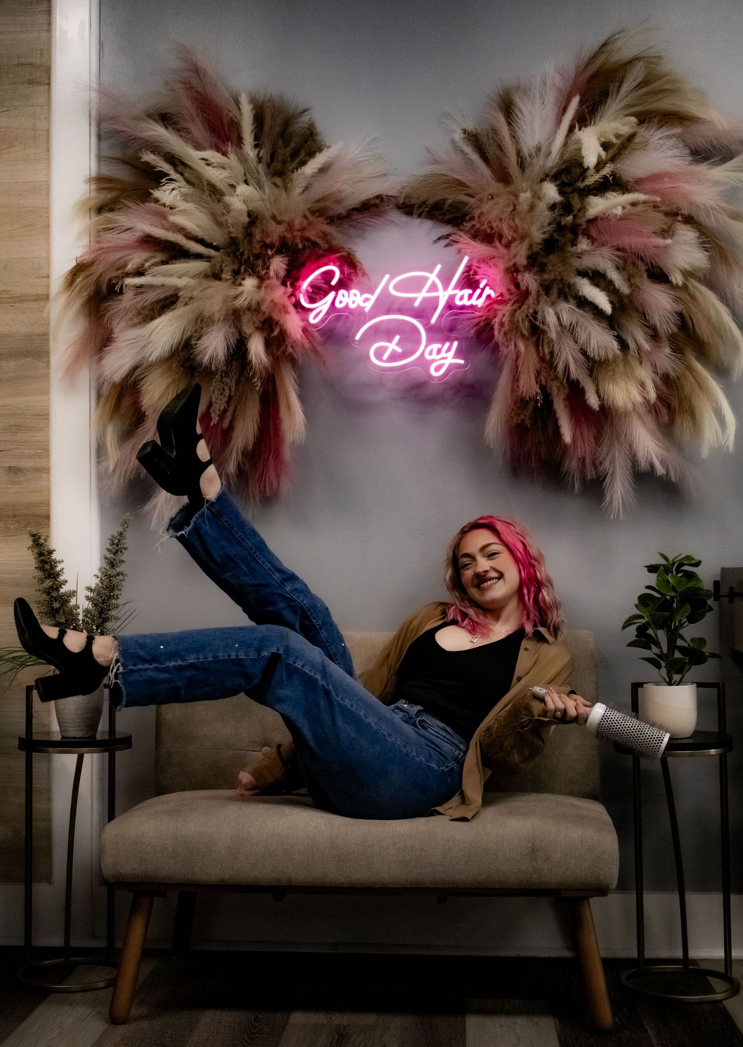Artistic photo series showing dynamic poses on a gray couch beneath a neon pink sign and dried pampas grass.