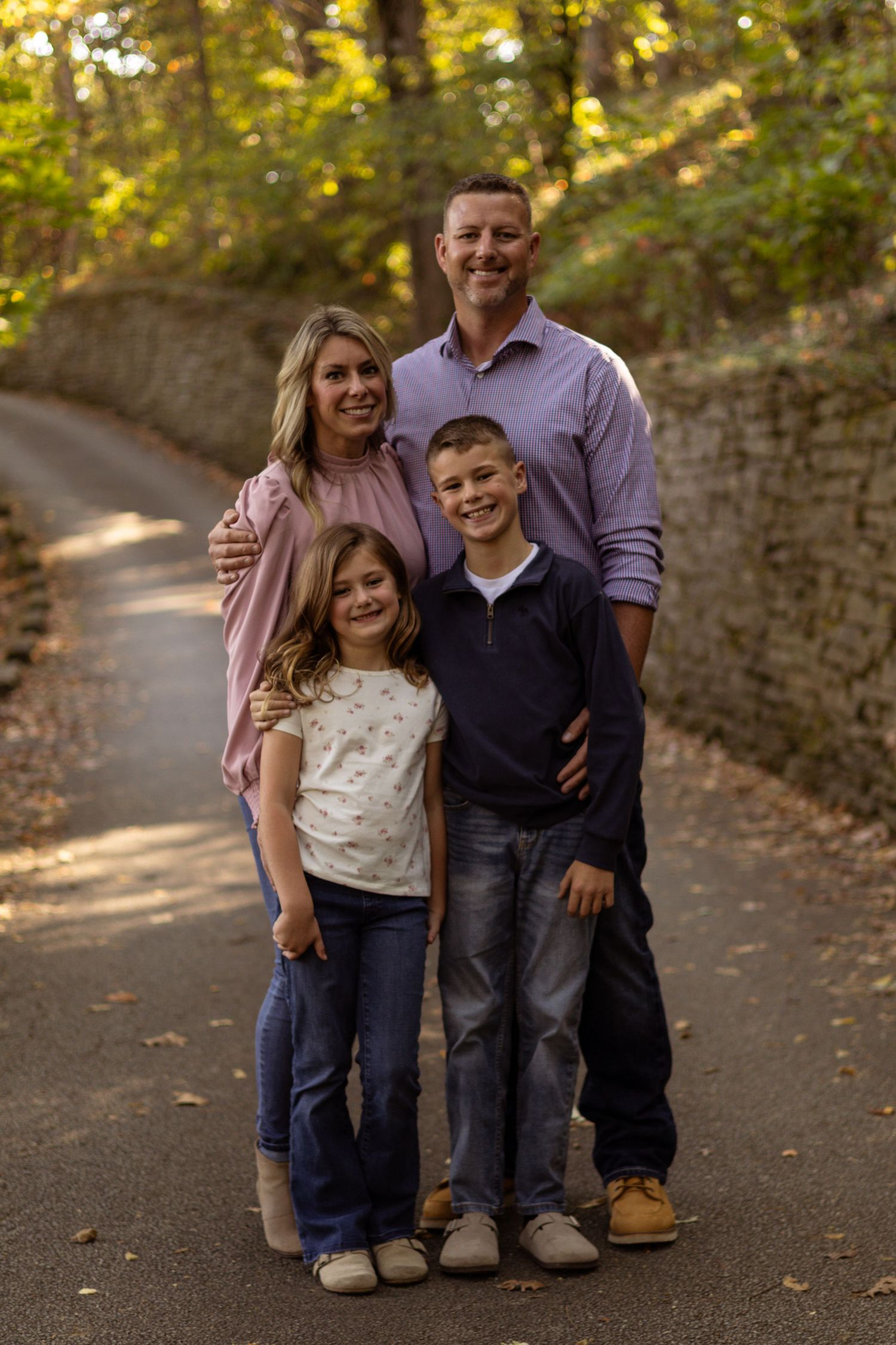 Family poses together on stone-lined path during autumn photo session.