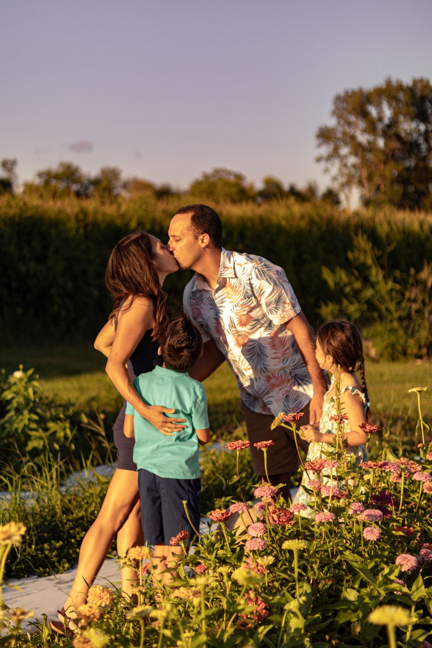 A family shares an intimate moment among blooming flowers at sunset.