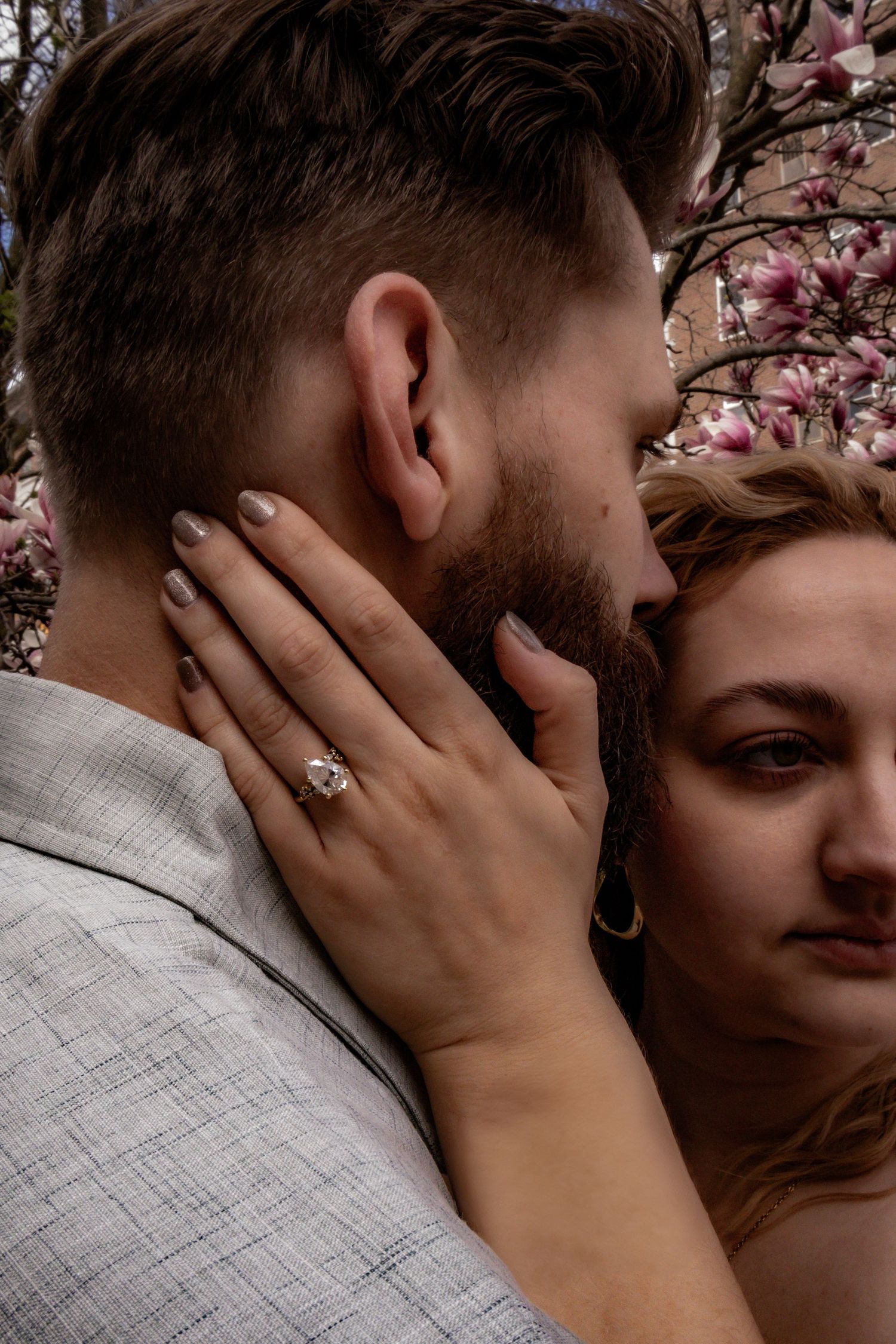Close-up romantic portrait with cherry blossoms blooming in the background.