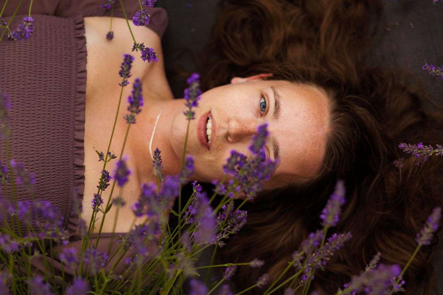 Artistic portrait with purple lavender flowers in natural lighting.