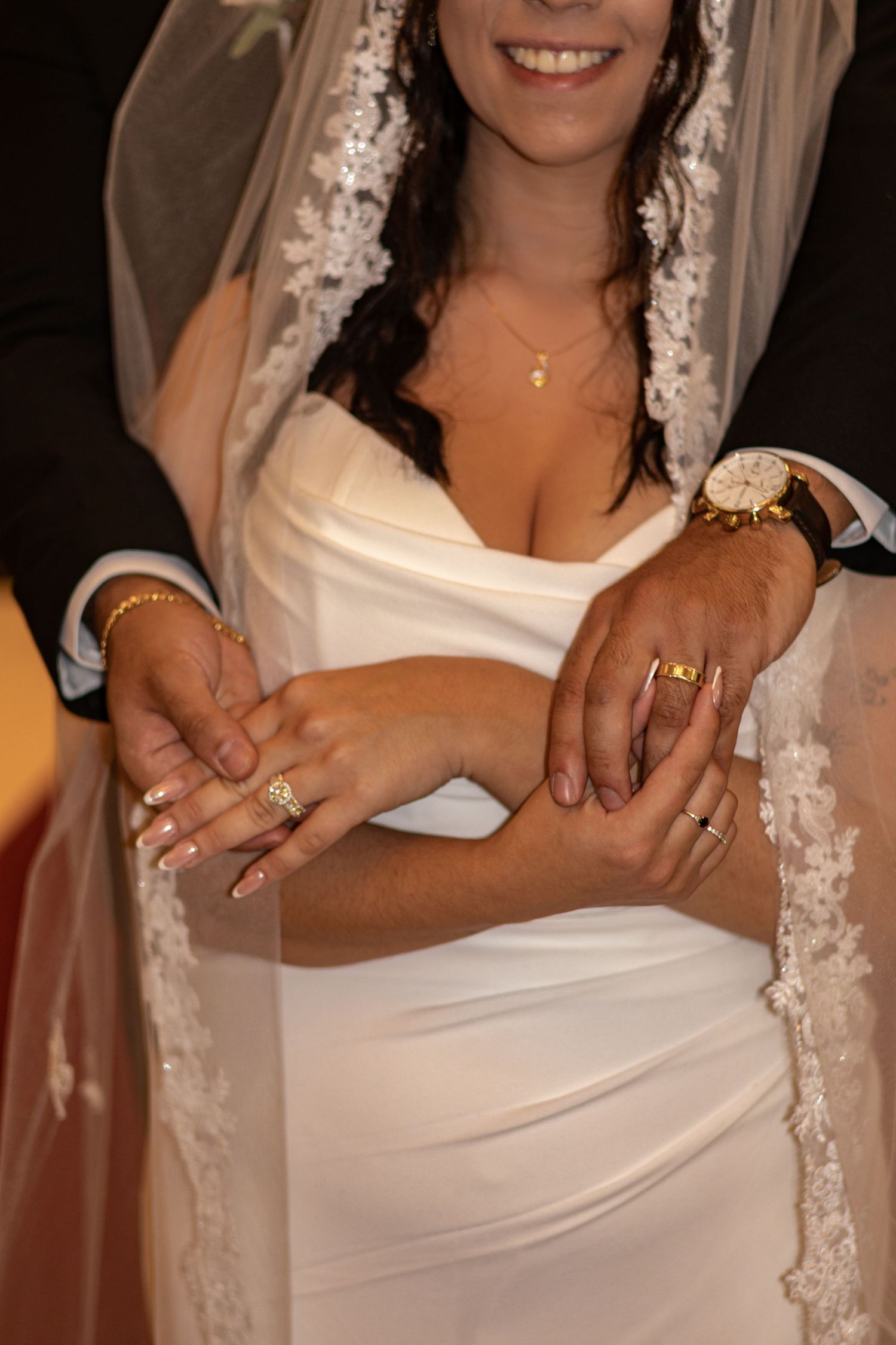 Close-up detail of wedding dress with lace veil and jewelry.