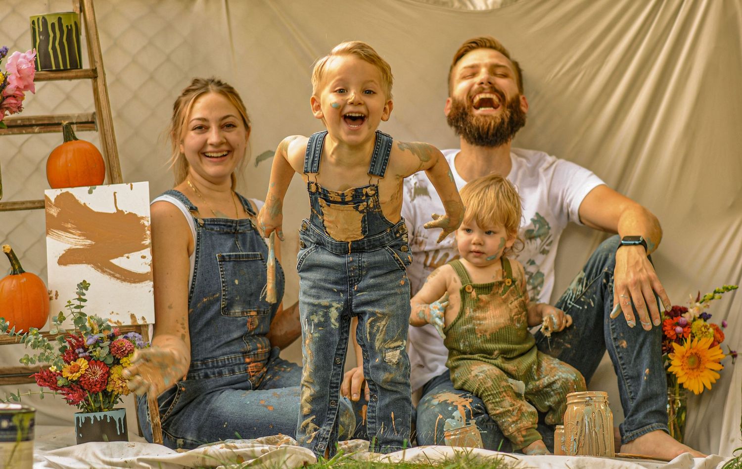 Autumn-themed scene with pumpkins, sunflowers, and overalls against a neutral backdrop.