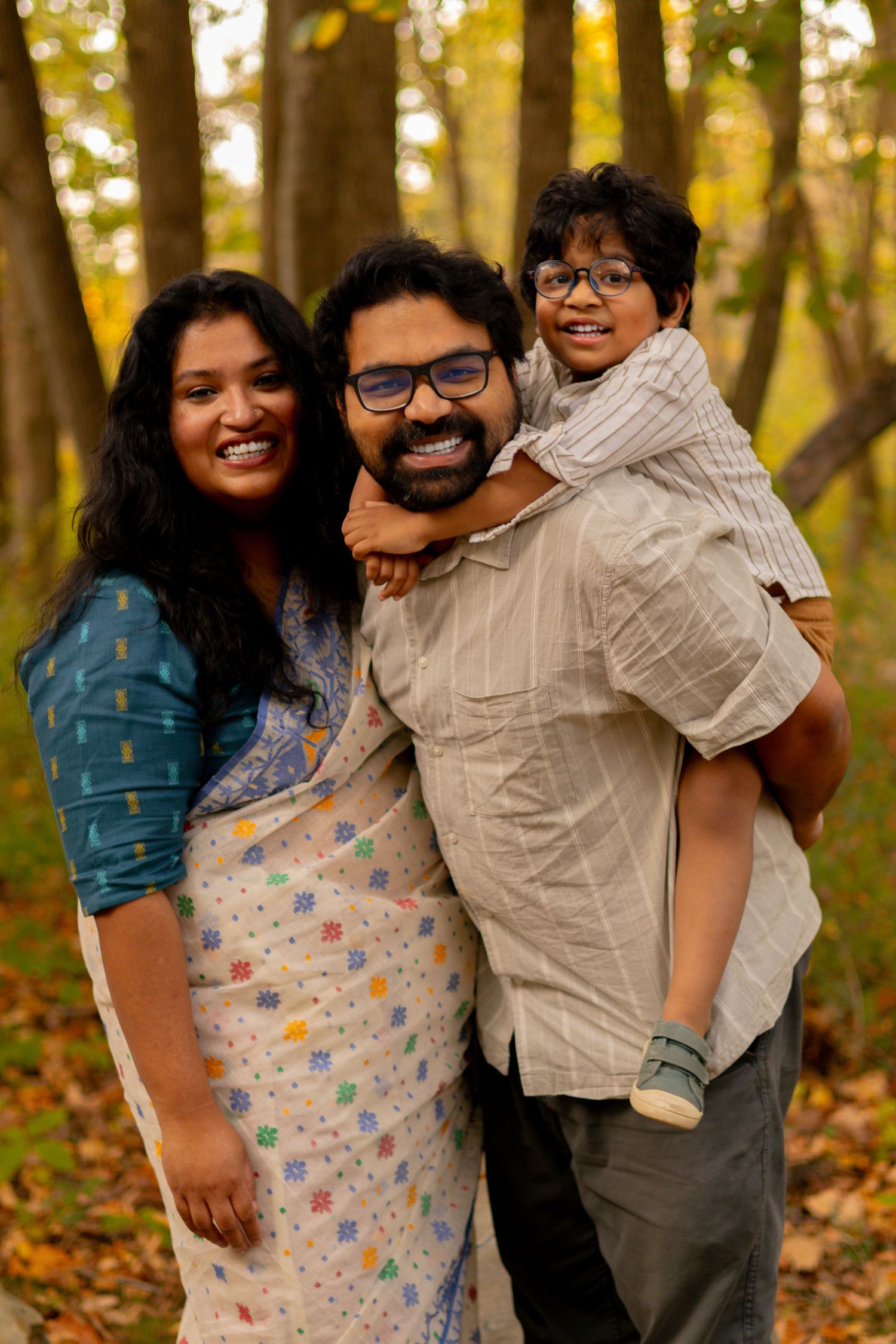 A family poses for a portrait in a wooded area with warm autumn colors.