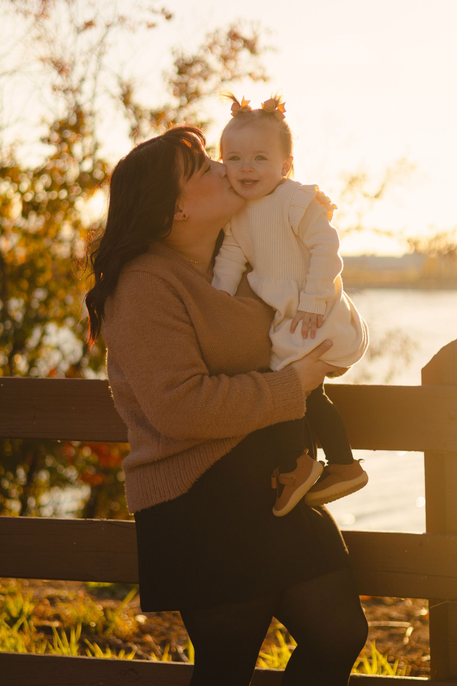 Tender moments shared on a wooden bench during golden hour sunset.