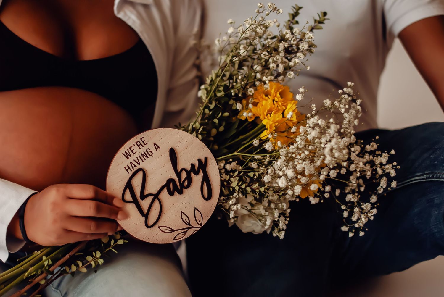 A wooden round sign reading 'Baby' alongside delicate white baby's breath flowers and yellow wildflowers.