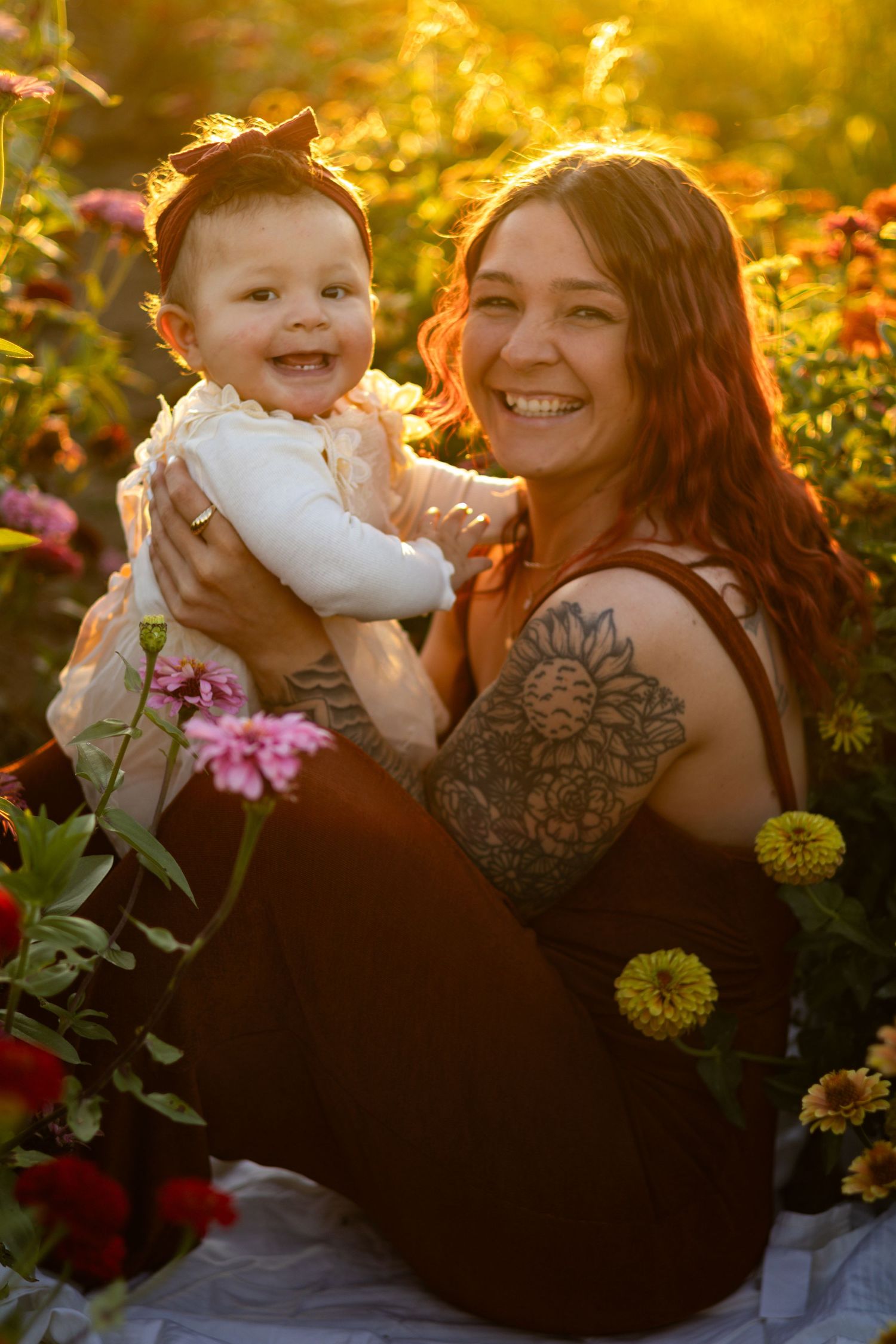 Tender moment captured in a garden with tattoos visible among blooming flowers at sunset.