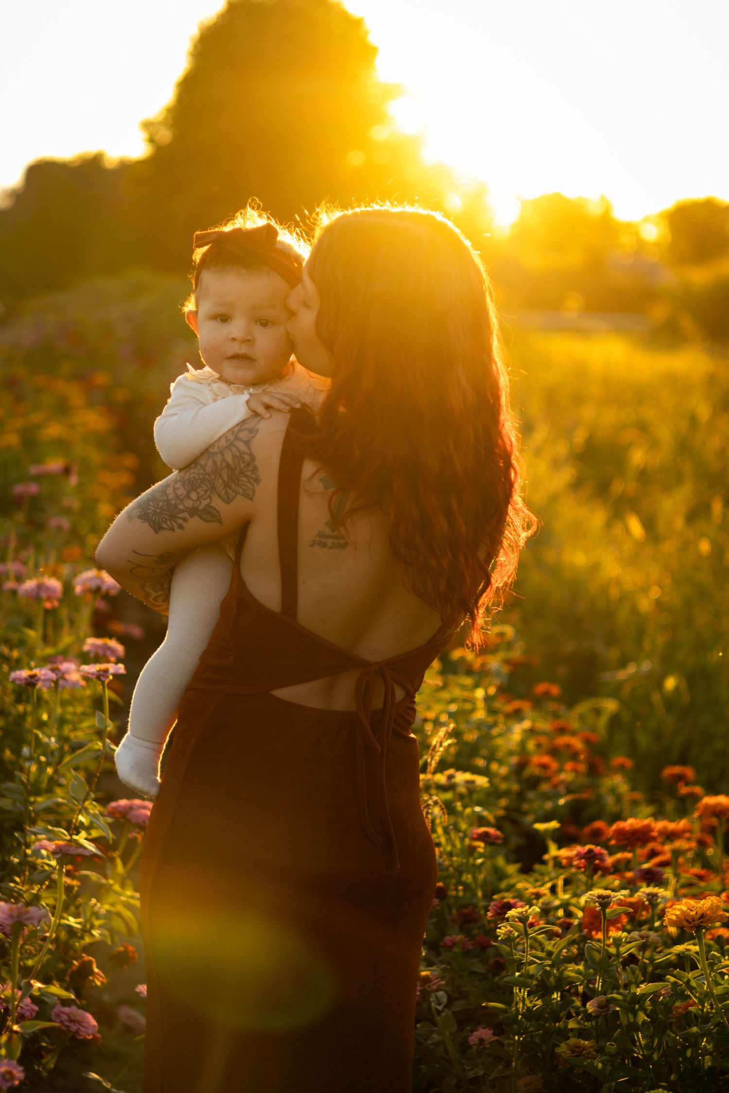 Sunset casts a warm glow over figures in a blooming flower garden.