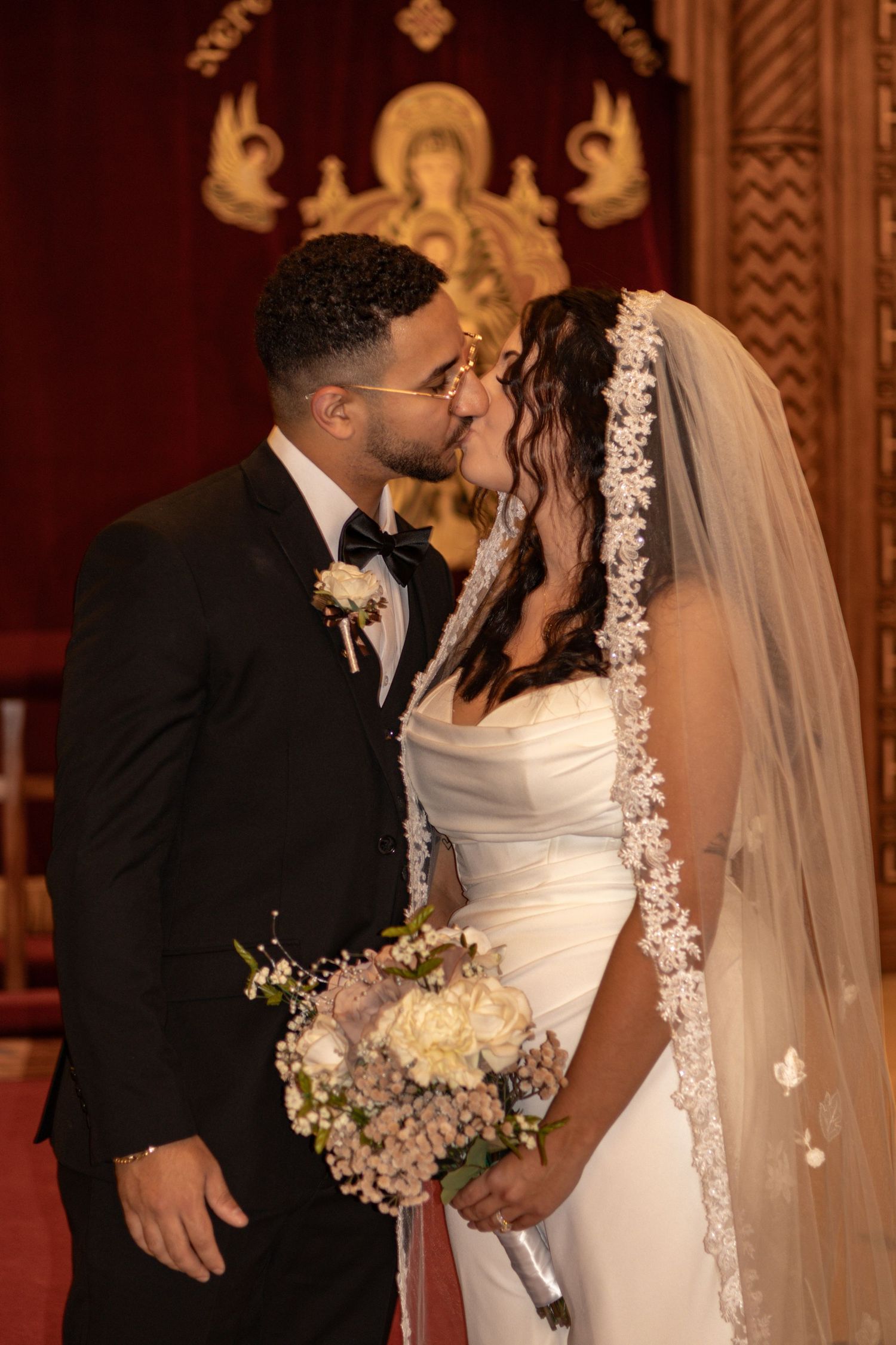 Traditional Orthodox church wedding ceremony with ornate religious artwork in background.