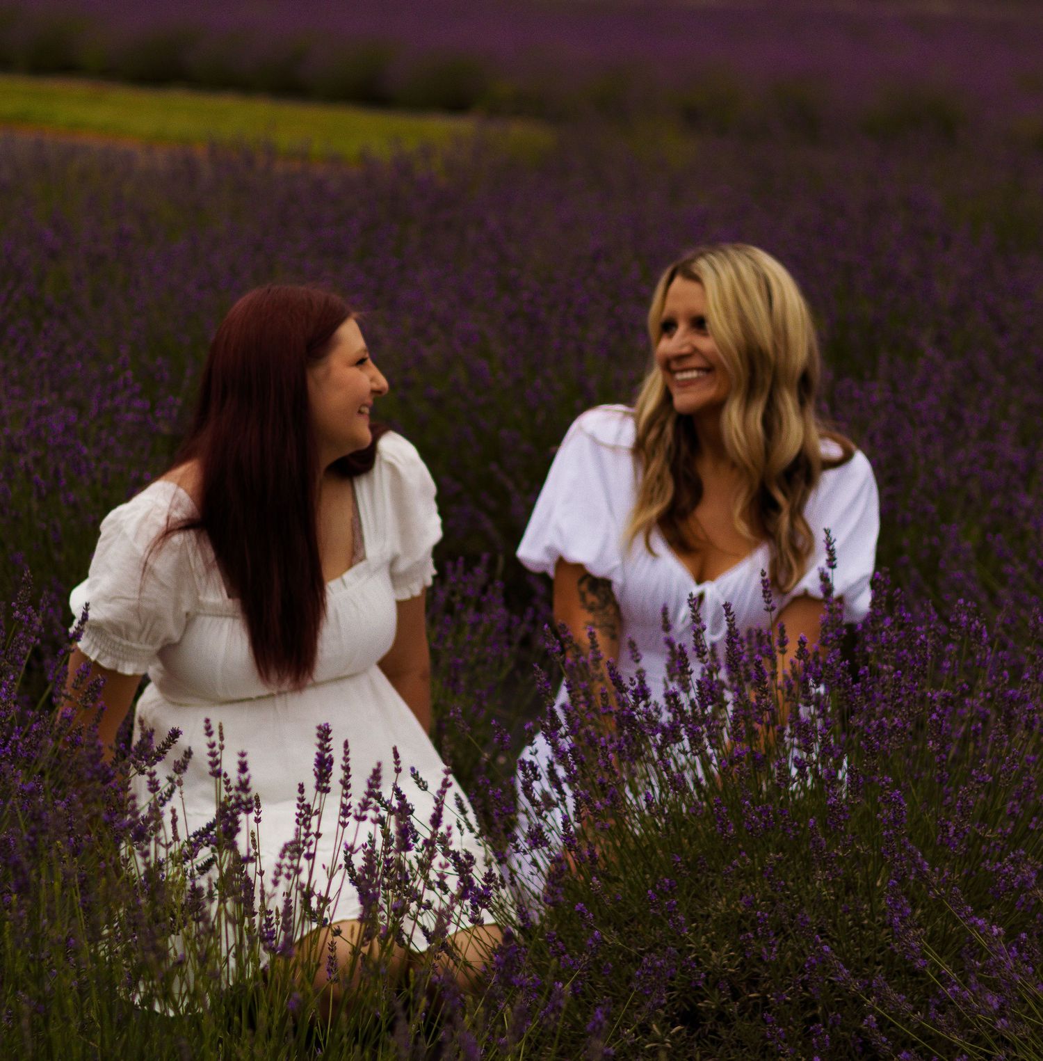 Friends sitting among purple lavender flowers during an outdoor photo session.