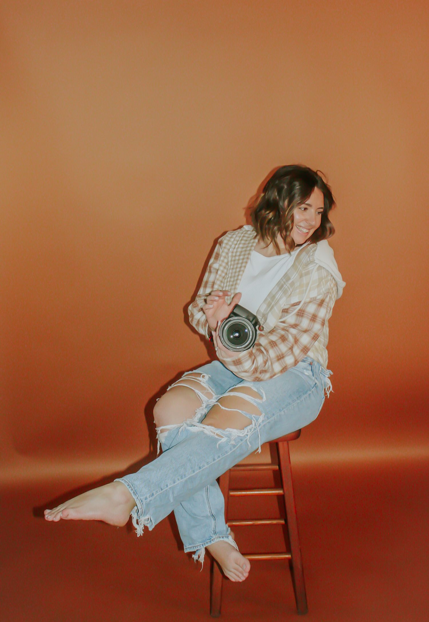 Artistic photo series in vintage style showing casual poses on wooden chair against orange backdrop.