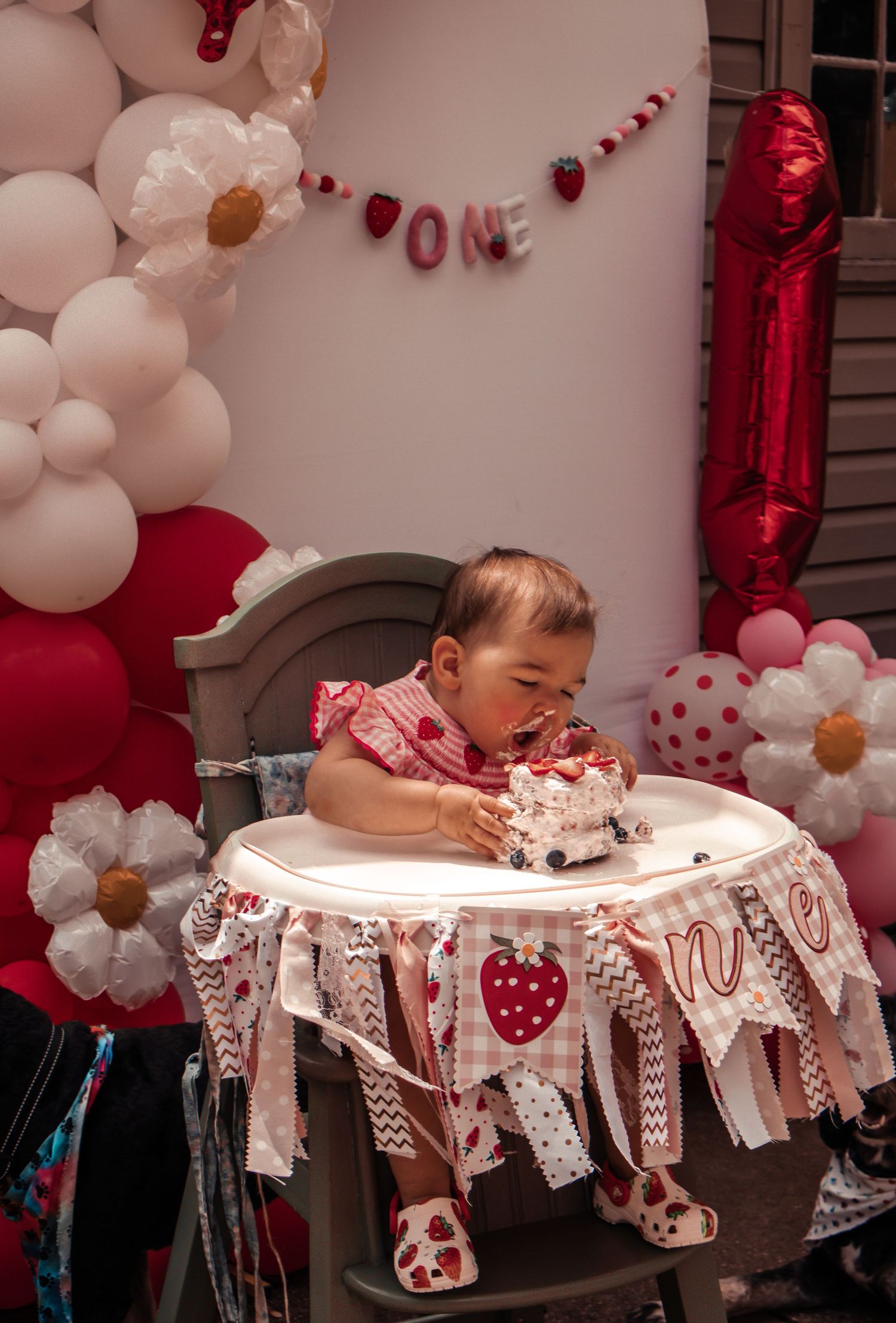 First birthday party setup with pink and white balloons and decorative bunting.