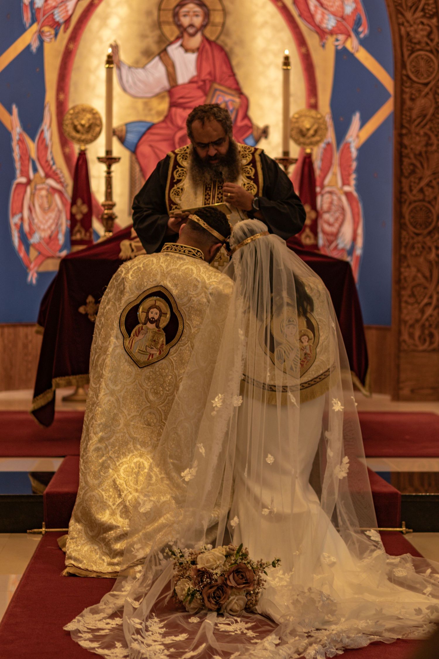 Orthodox wedding ceremony taking place in front of colorful religious iconography.