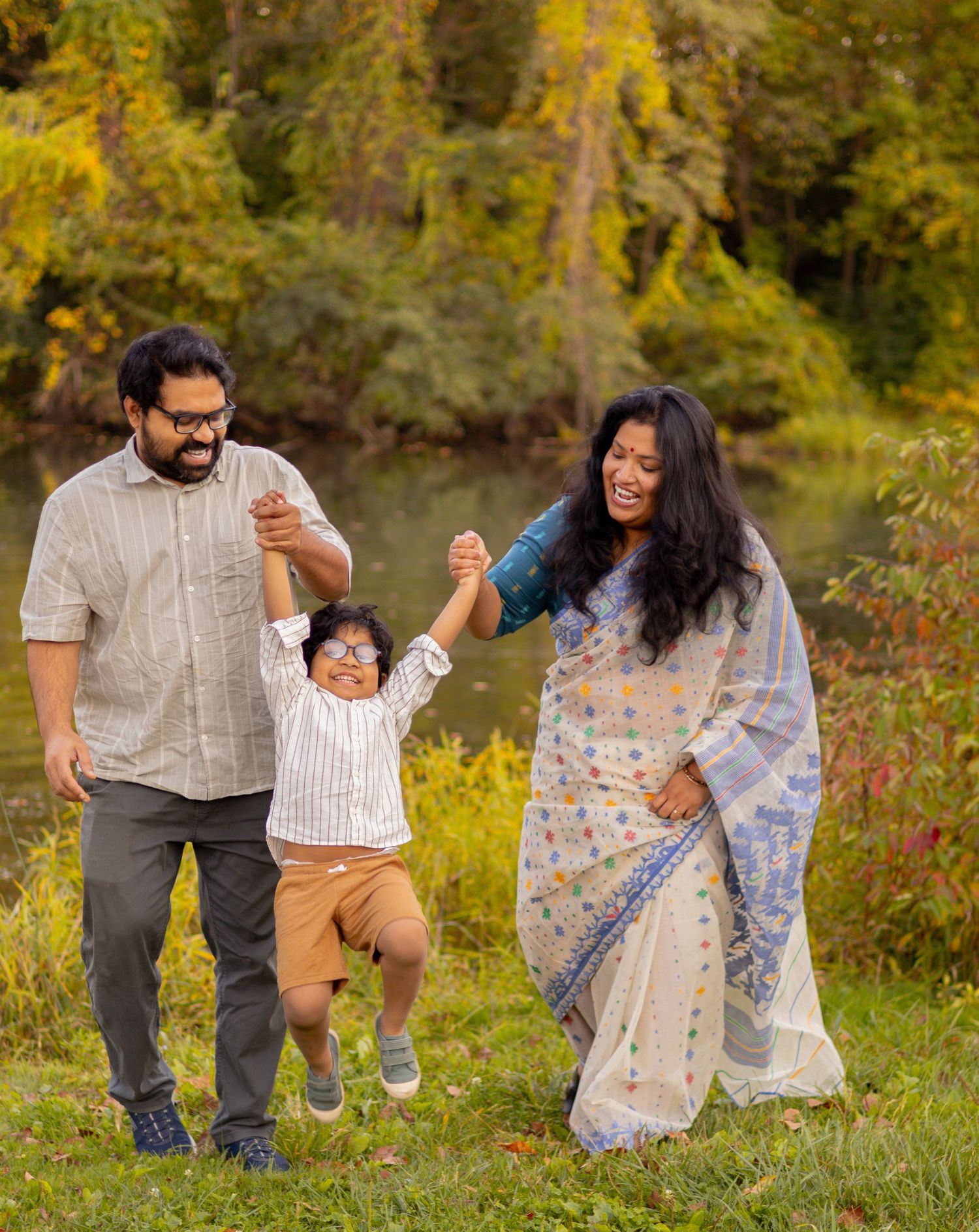 A family holds hands while jumping together in a scenic outdoor setting.