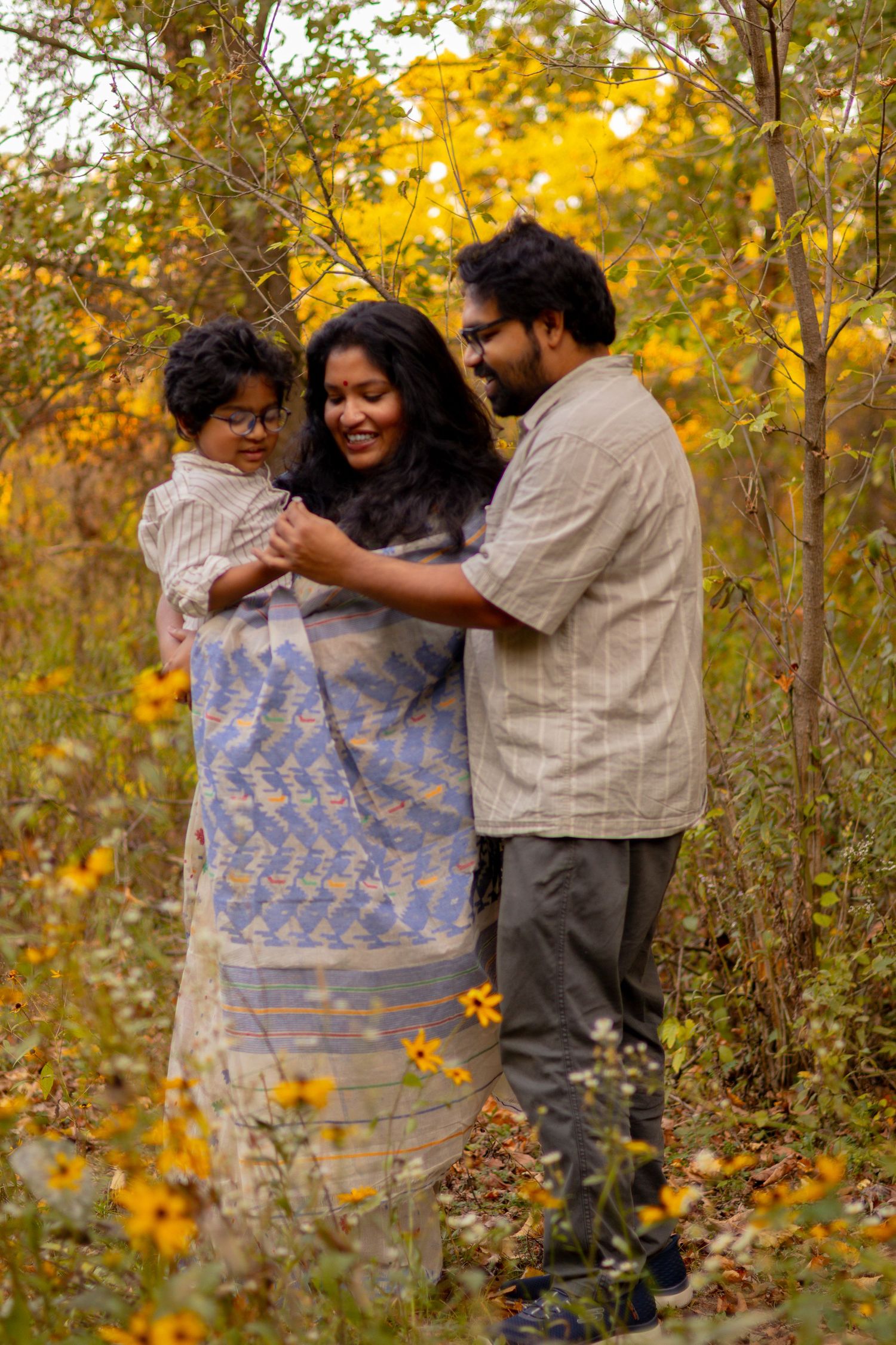 A family shares a tender moment together surrounded by golden autumn foliage.