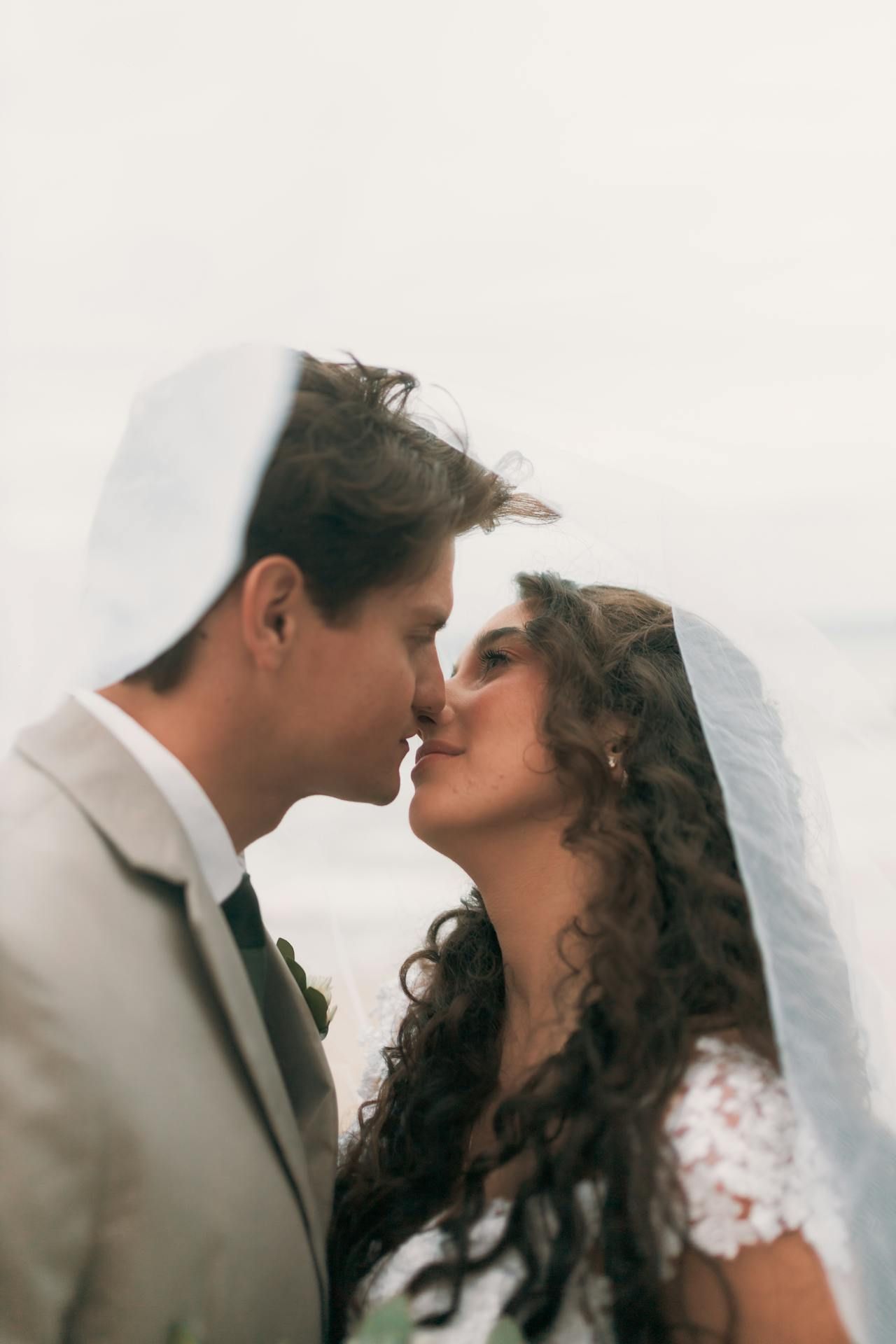 Romantic wedding moment: bride and groom kissing under veil at outdoor ceremony in Montreal.