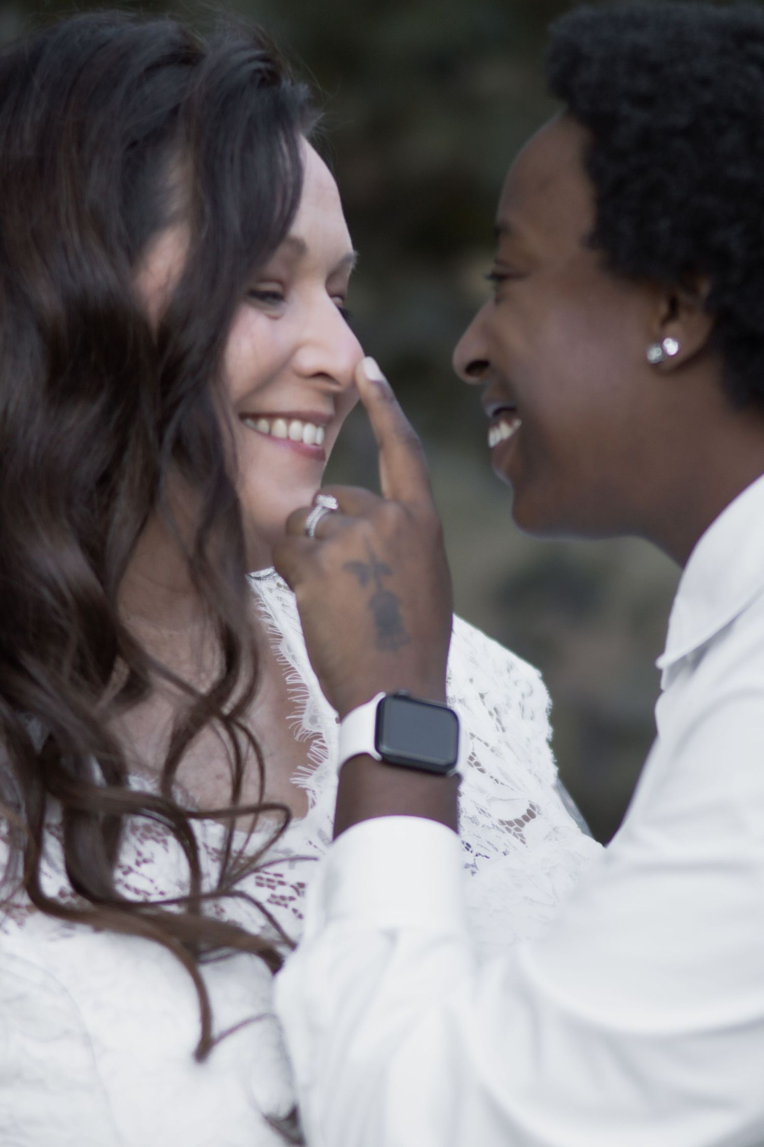 An intimate moment between a couple in white clothing sharing laughter and gentle touches.