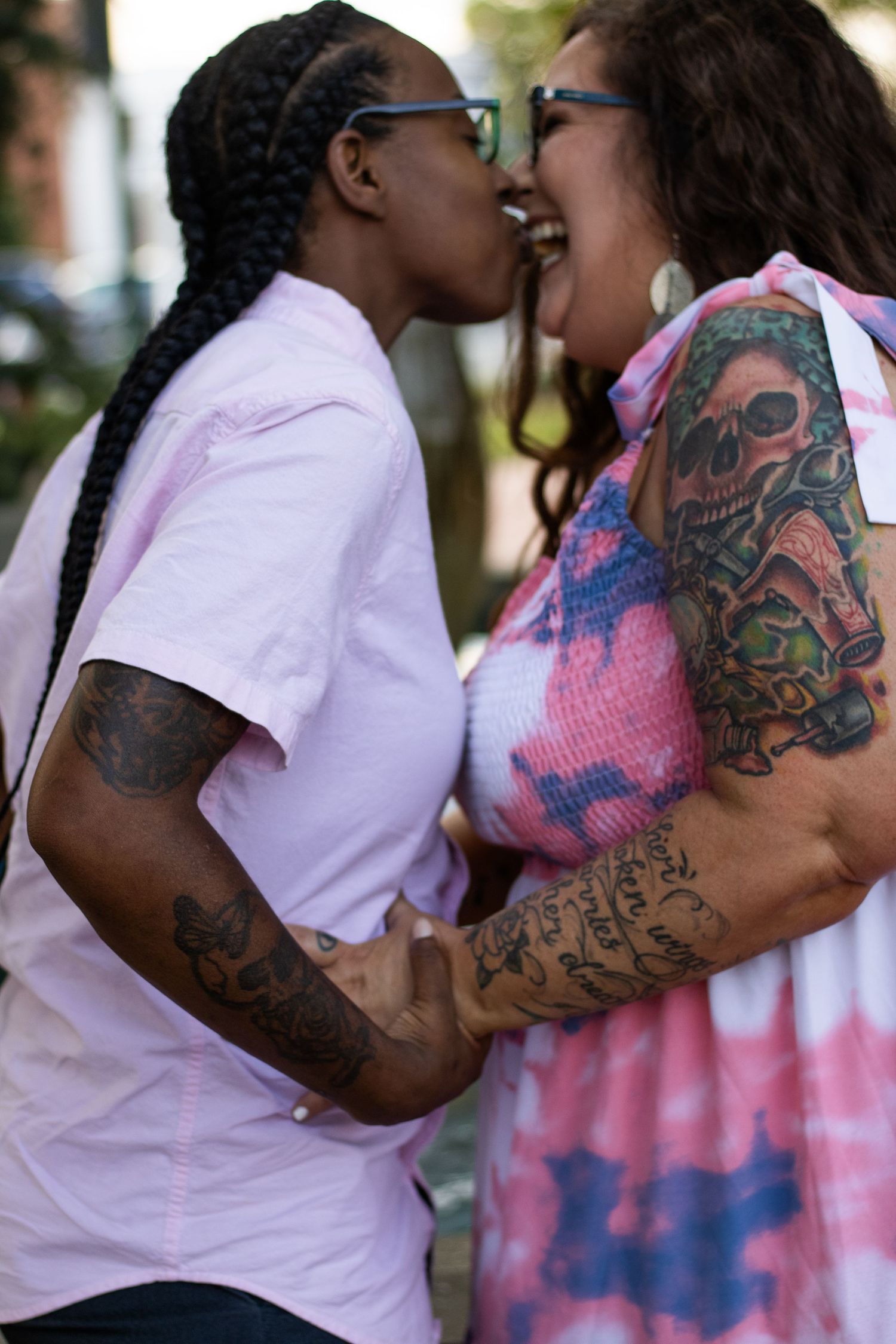 Happy couple sharing intimate moment outdoors, showing visible tattoos and genuine emotion.