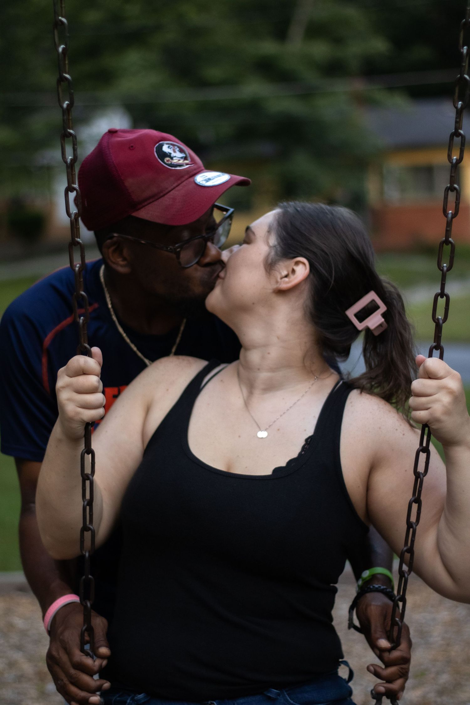 Couple sharing romantic moments on playground swings at sunset.