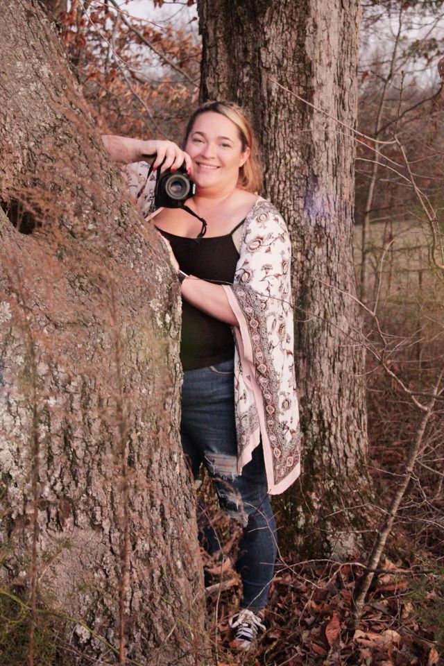 Photography session in autumn woods with rustic tree trunks and fallen leaves.