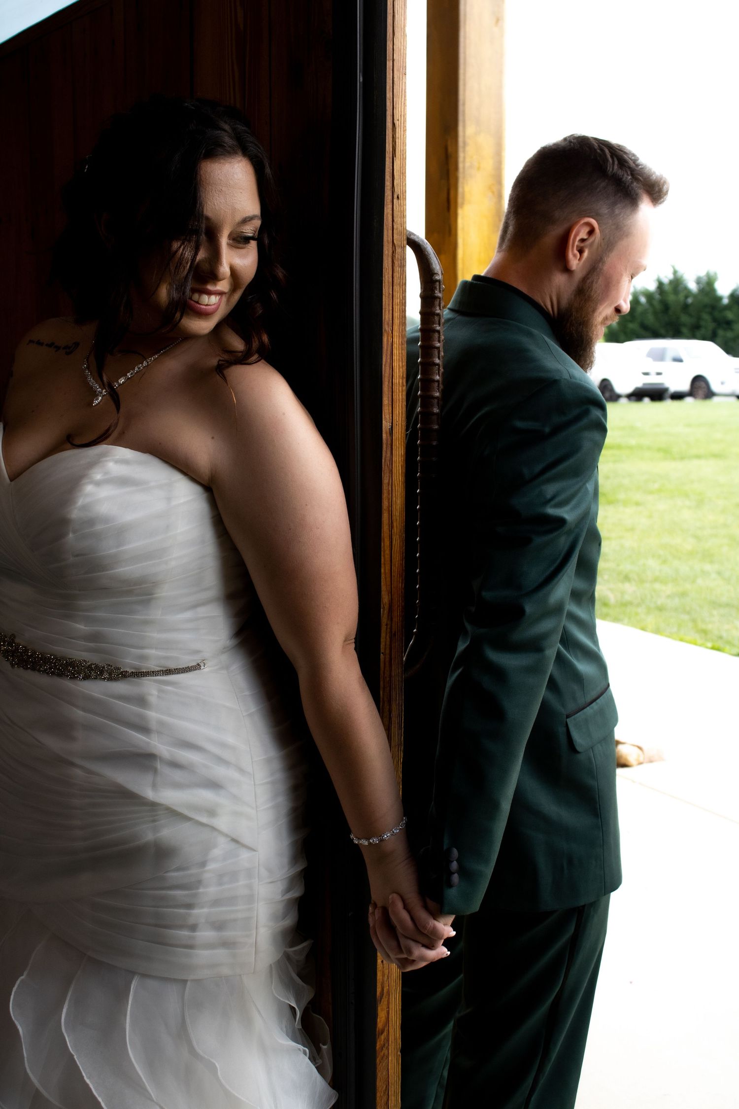 Couple shares intimate moment on opposite sides of wooden door before ceremony.