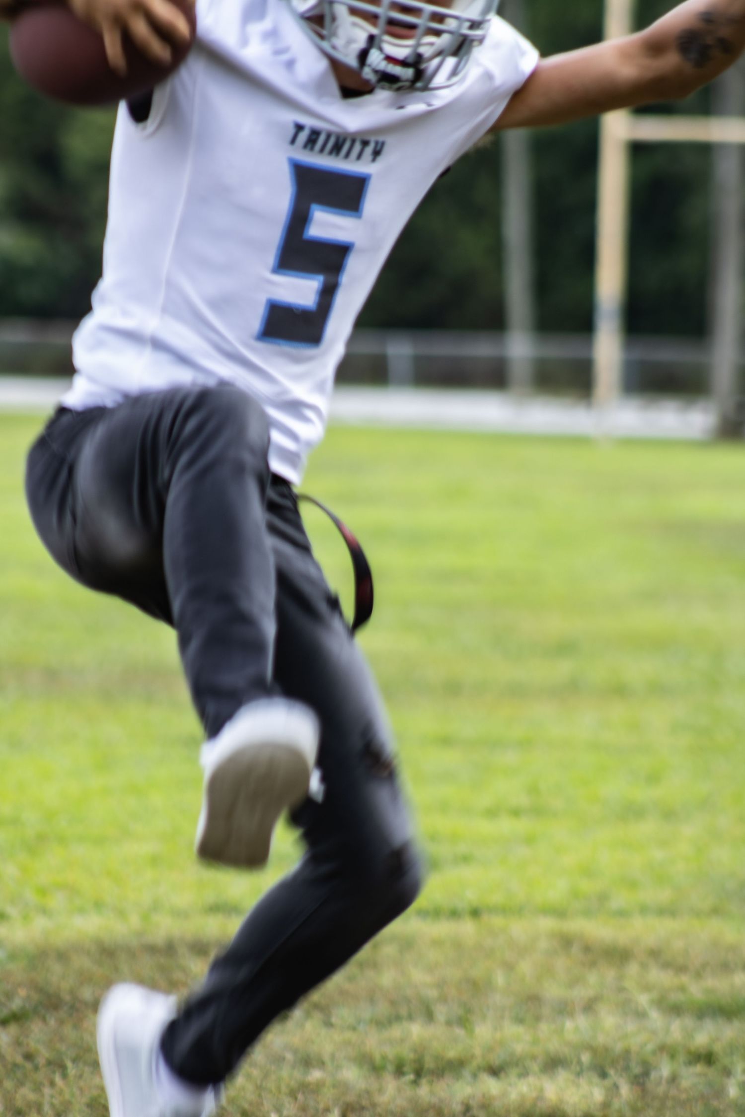 Action shot of a Trinity football player wearing jersey number 5 in motion on the field.