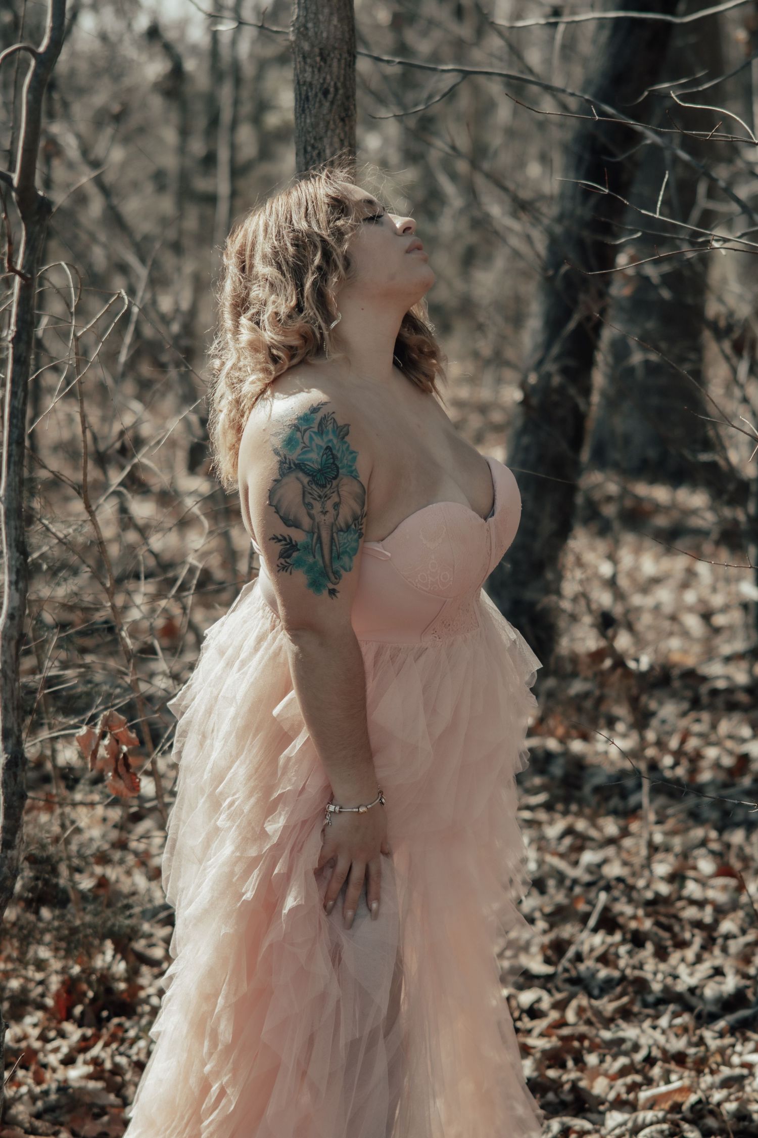 Ethereal figure in a pink tulle dress walks through misty autumn woods.