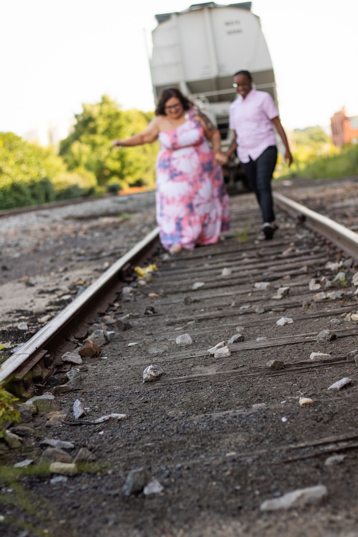 Playful couple running along railroad tracks during an engagement photoshoot.