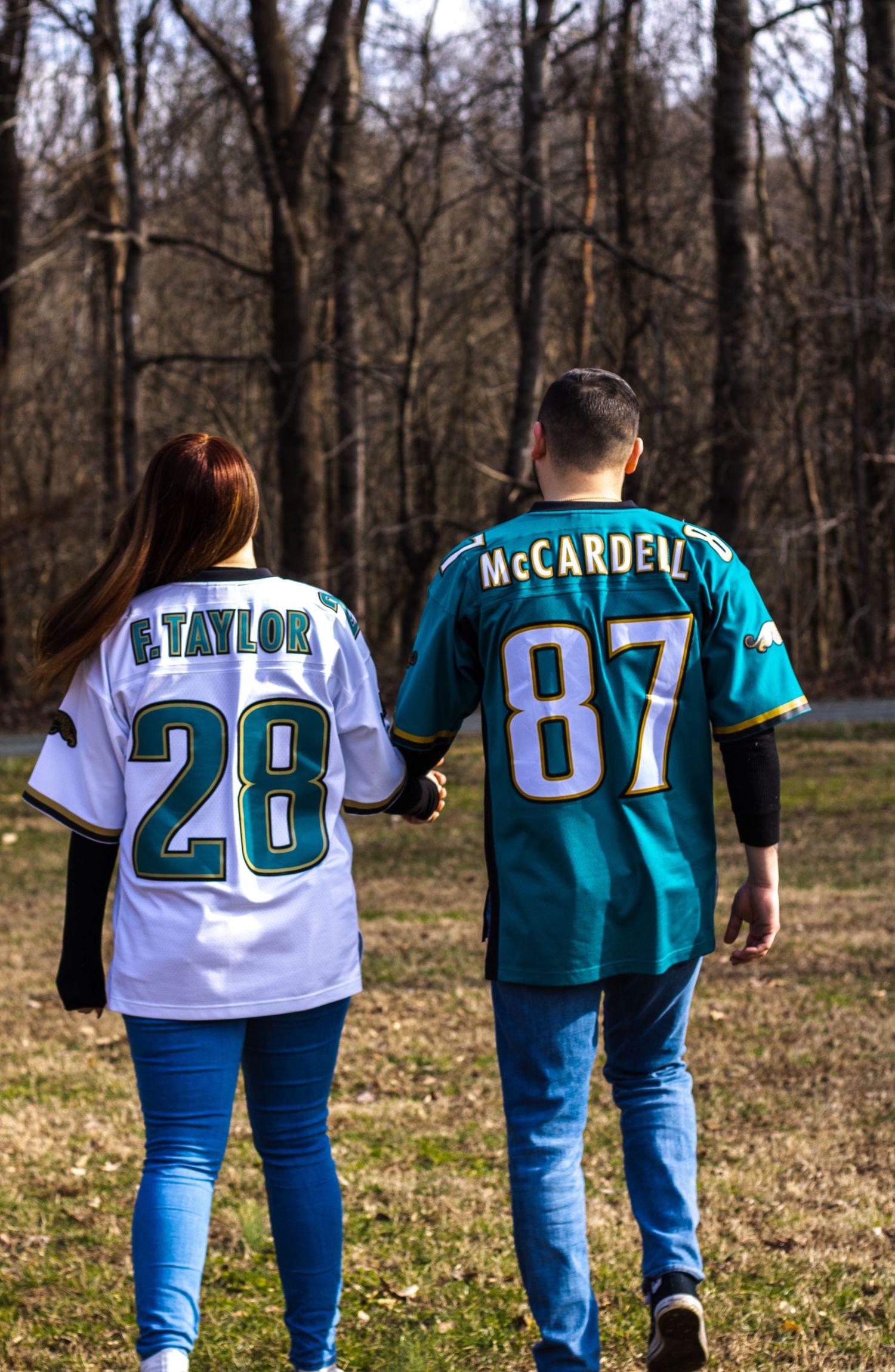 Row of sports jerseys with numbers and team names walking through a wooded area.