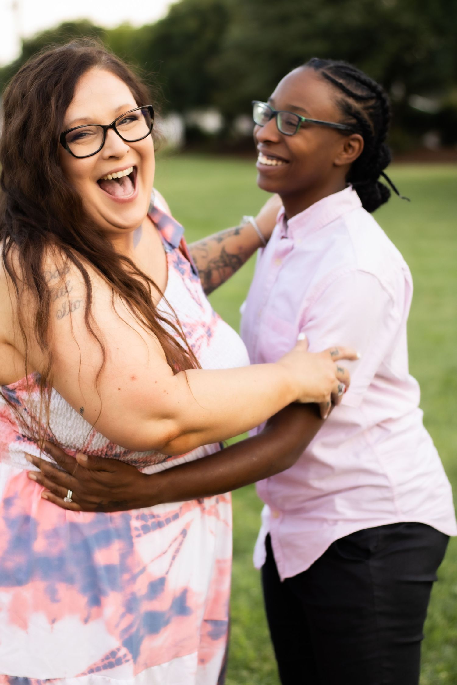 Joyful couple laughing and embracing in a park setting while wearing coordinated outfits.