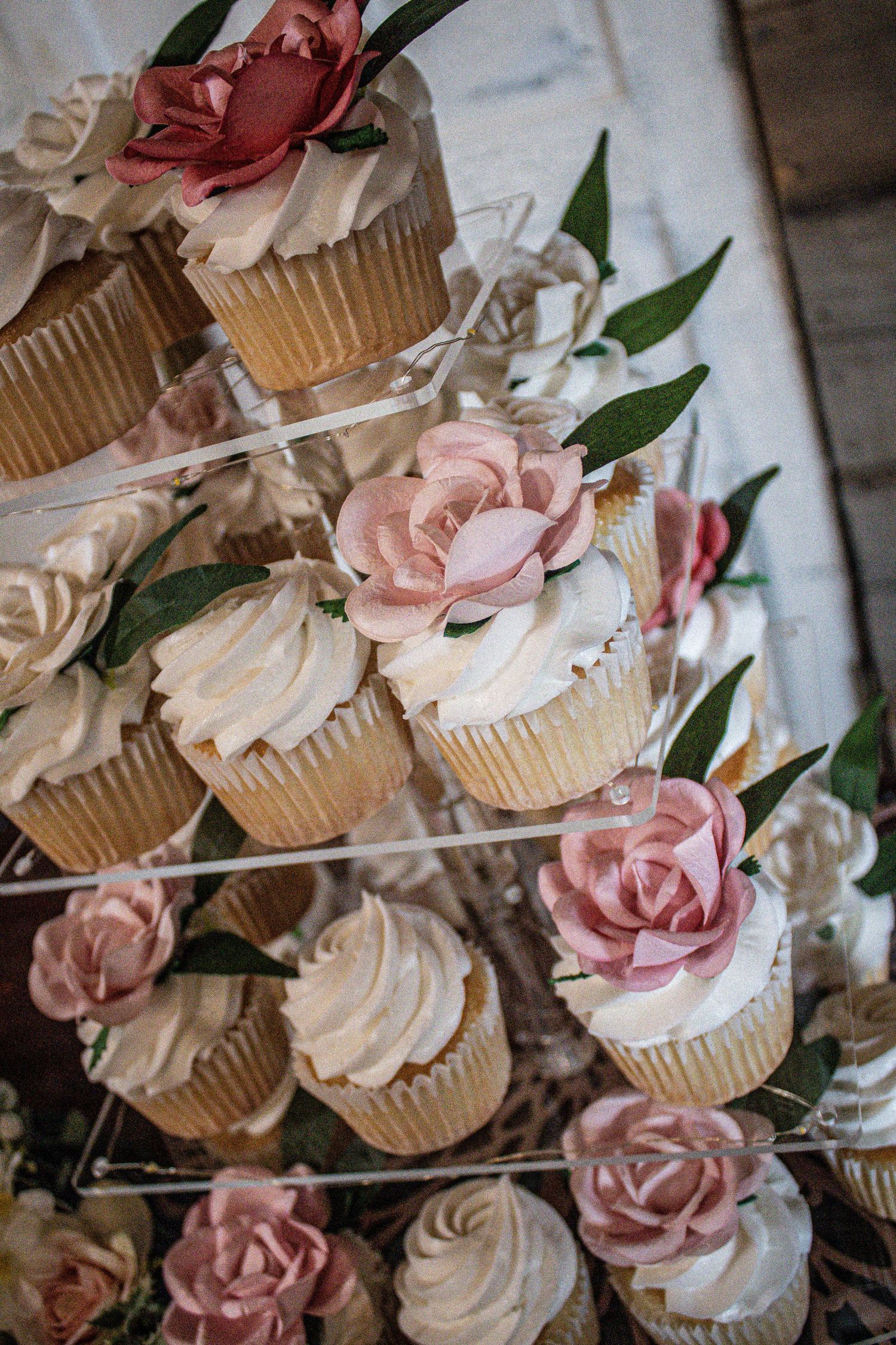 Beautiful cupcake display with pink and white roses adorning each cupcake on a tiered stand.