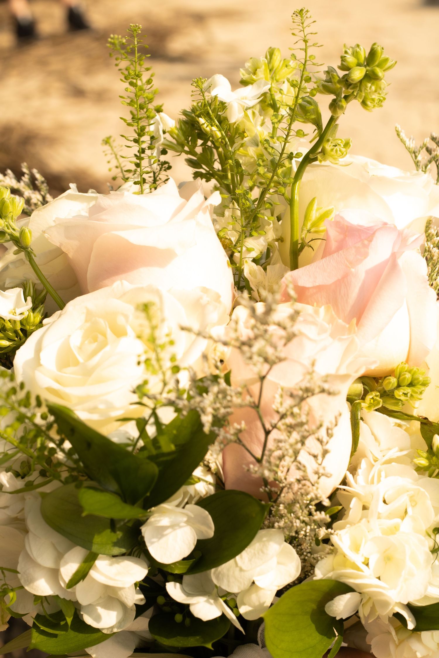 A delicate arrangement of white and pink roses with greenery in soft natural light.