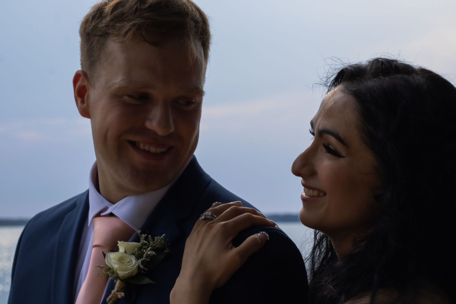 A tender sunset moment between newlyweds against a waterfront backdrop.