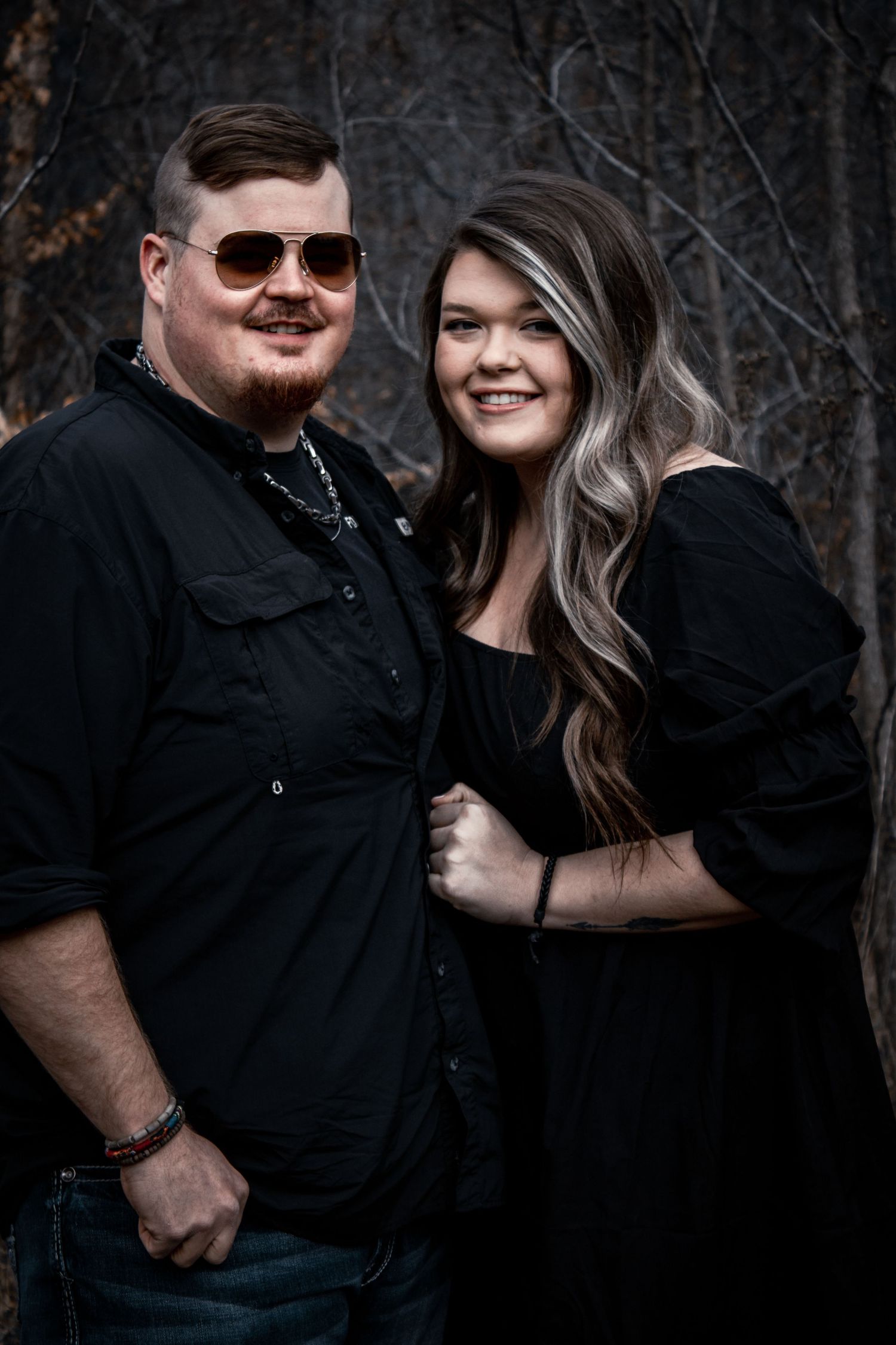 Couple in black clothing embracing during a romantic outdoor photoshoot.