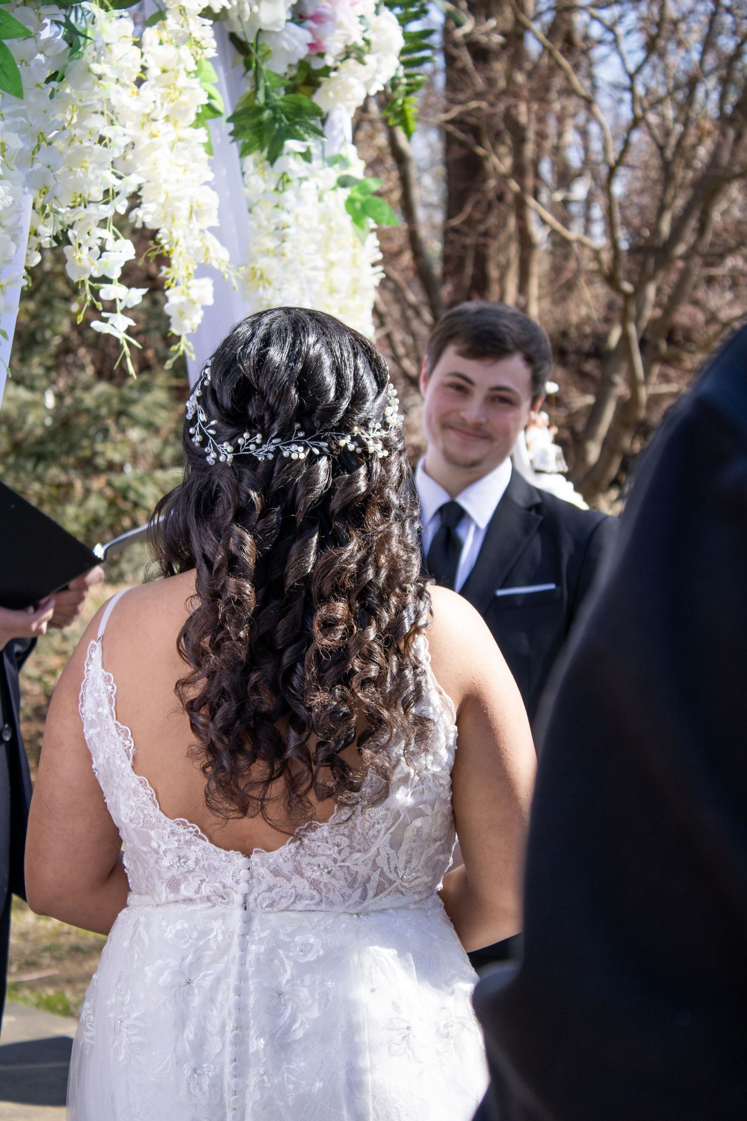 Wedding ceremony details showing bride's lace dress and floral decorations.