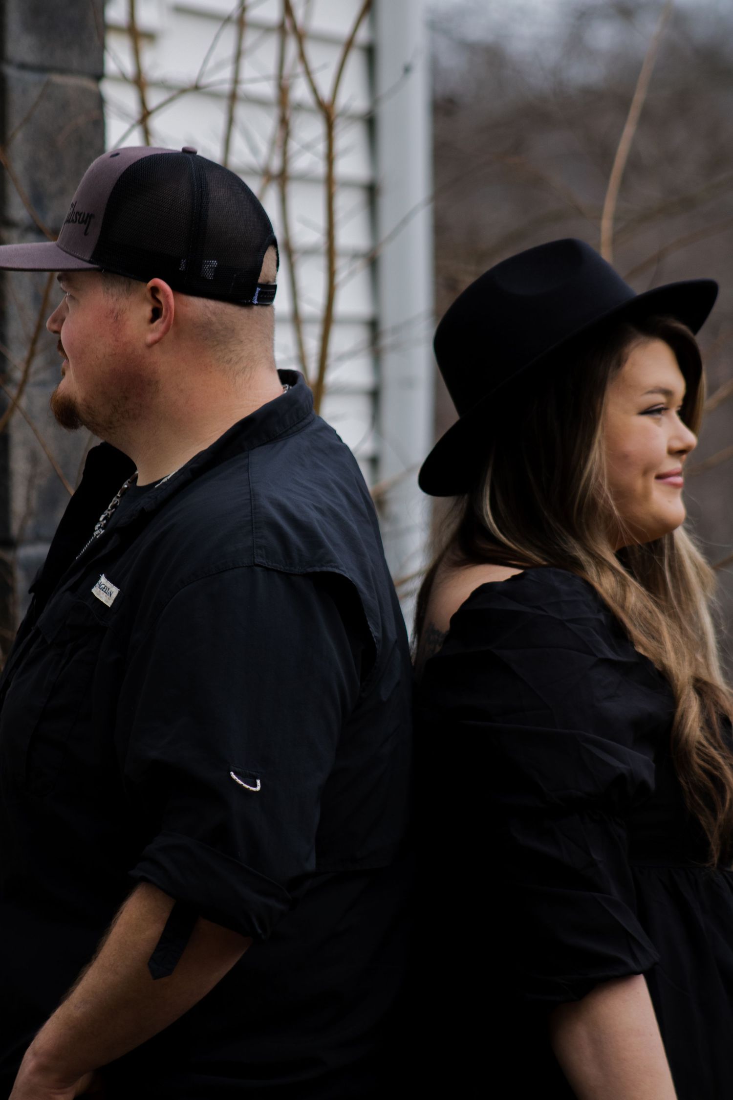 Couple in matching black outfits sharing a candid moment outdoors.