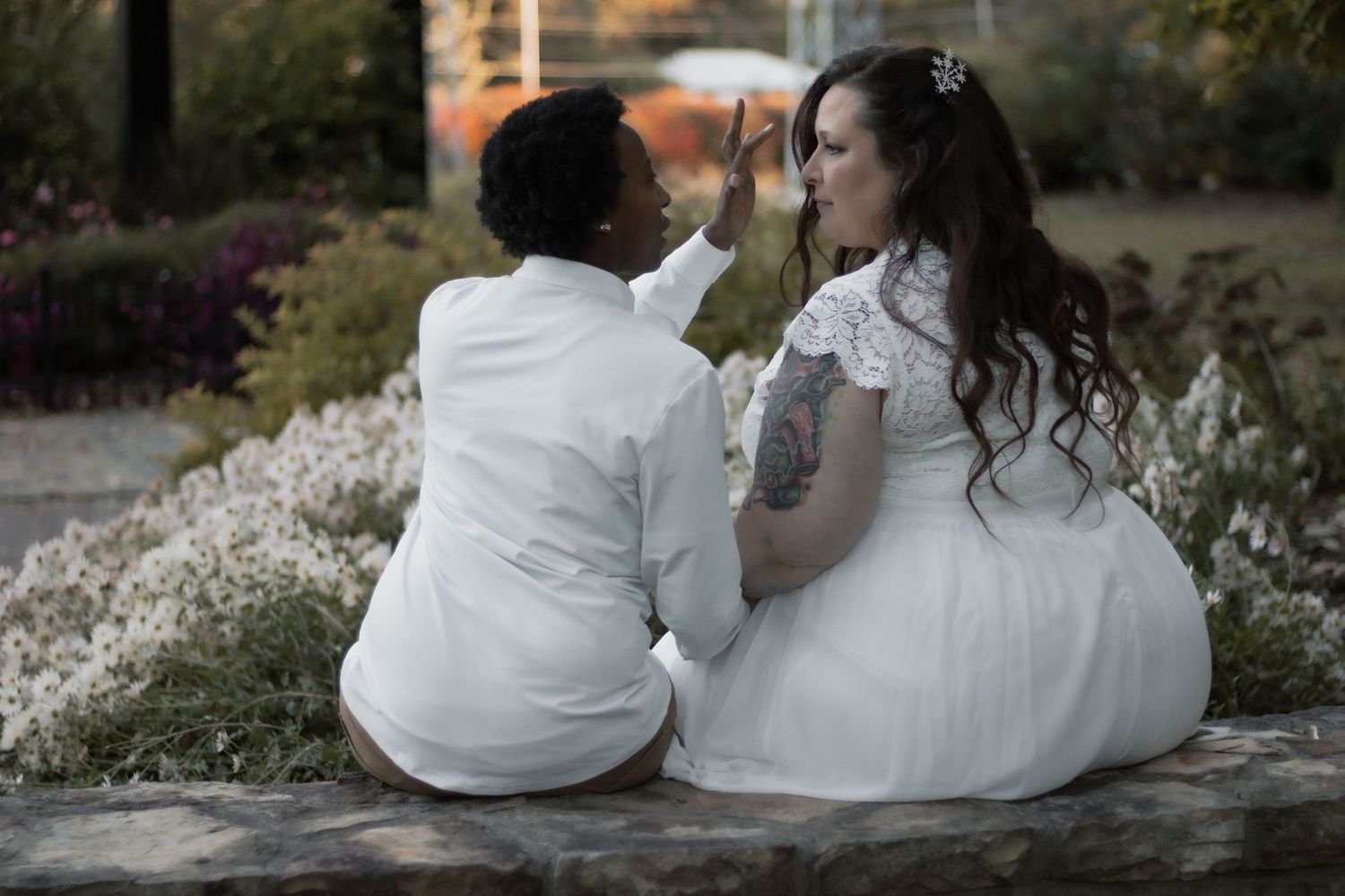 Couple in matching white outfits sharing tender moment outdoors.