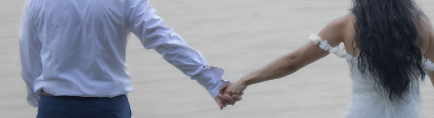 Close-up of joined hands between two people walking together.