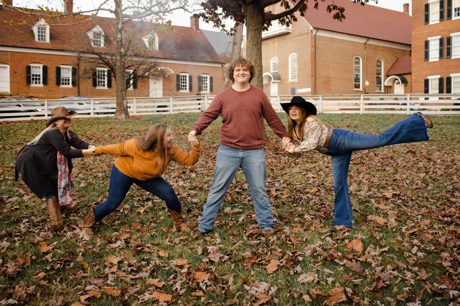 Group of friends playing and posing dramatically in pile of autumn leaves.