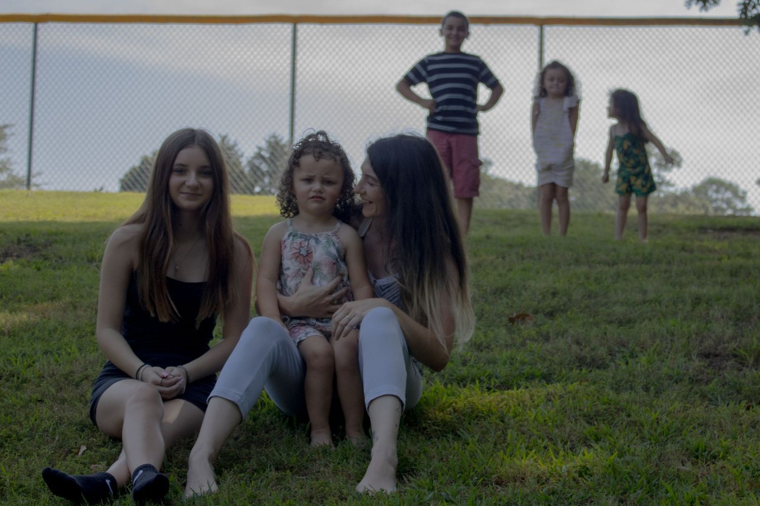 Group members relax together on a grassy hillside during sunset.