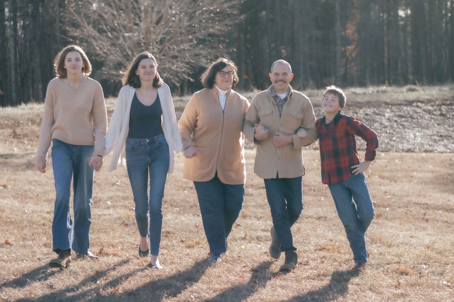 Group walking together on sunlit path through autumn scenery.