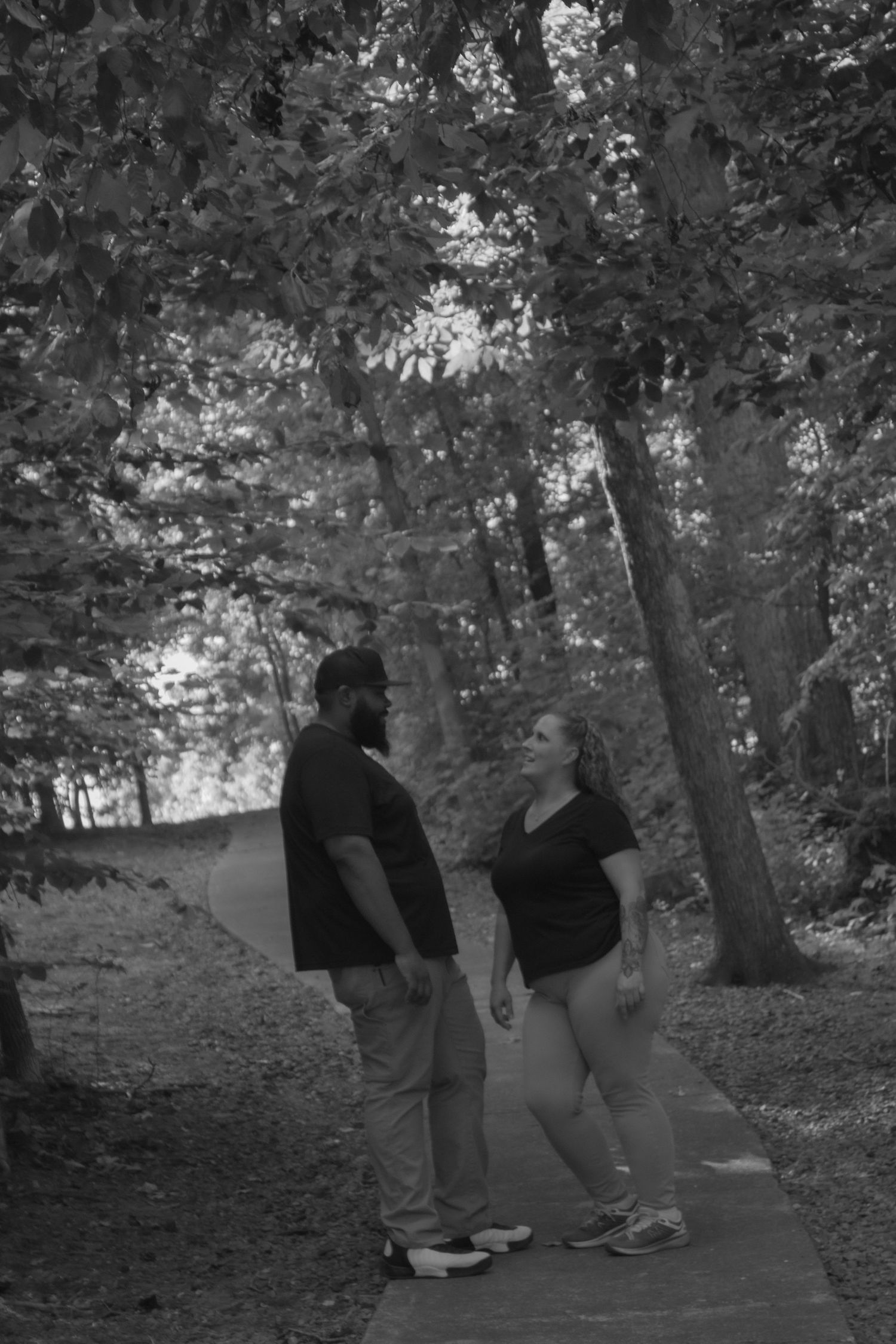 Two figures walk together on a tree-lined path in casual clothing.