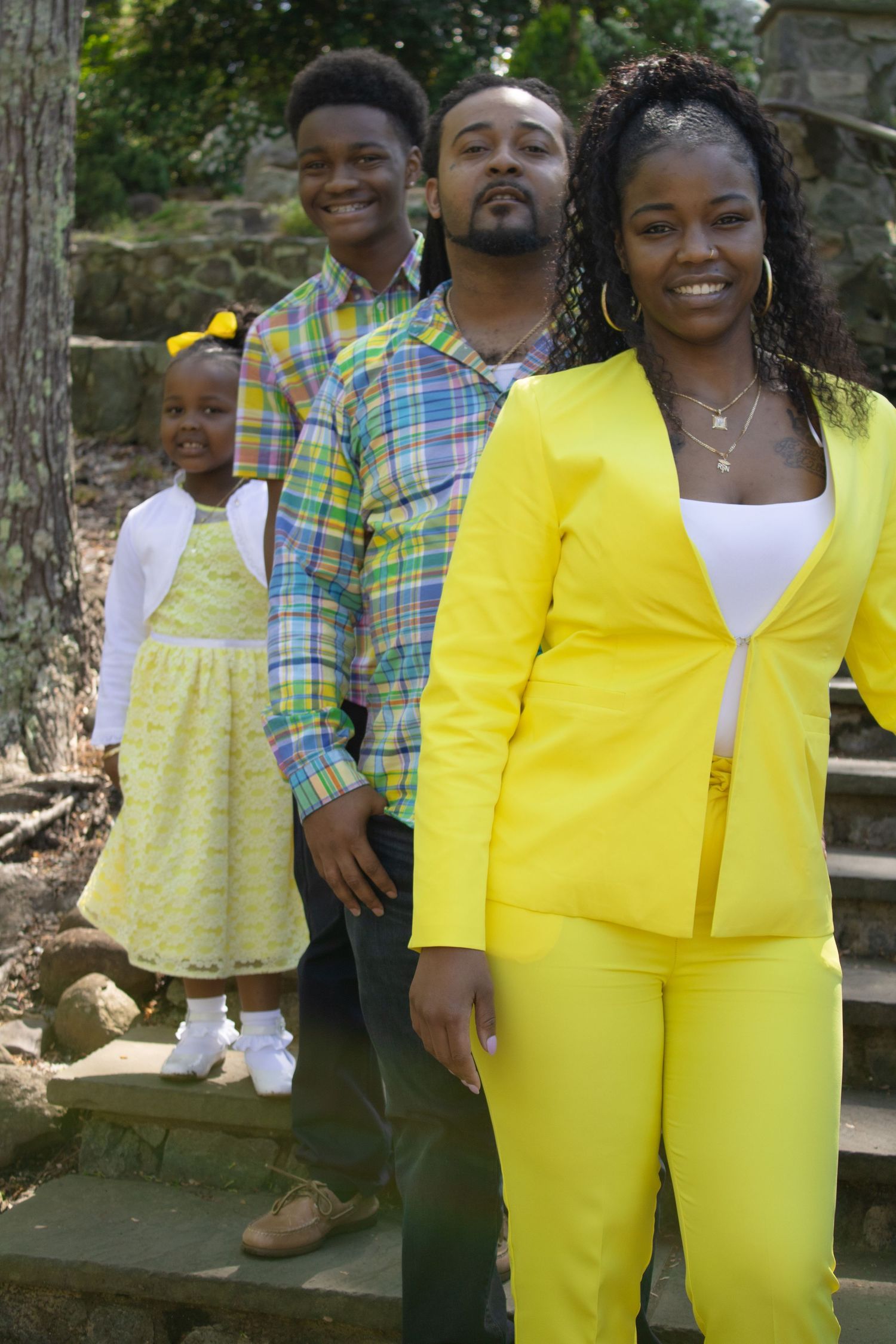 A family poses on stone steps wearing coordinated yellow and plaid outfits.