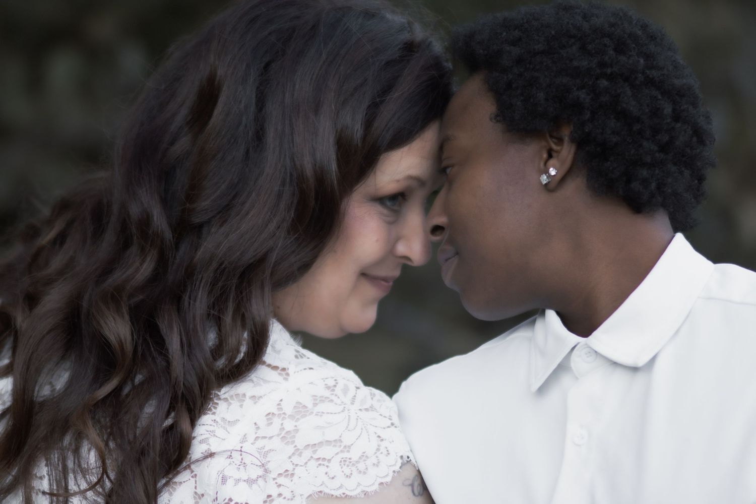 Close-up romantic moment between couple wearing coordinated white outfits.