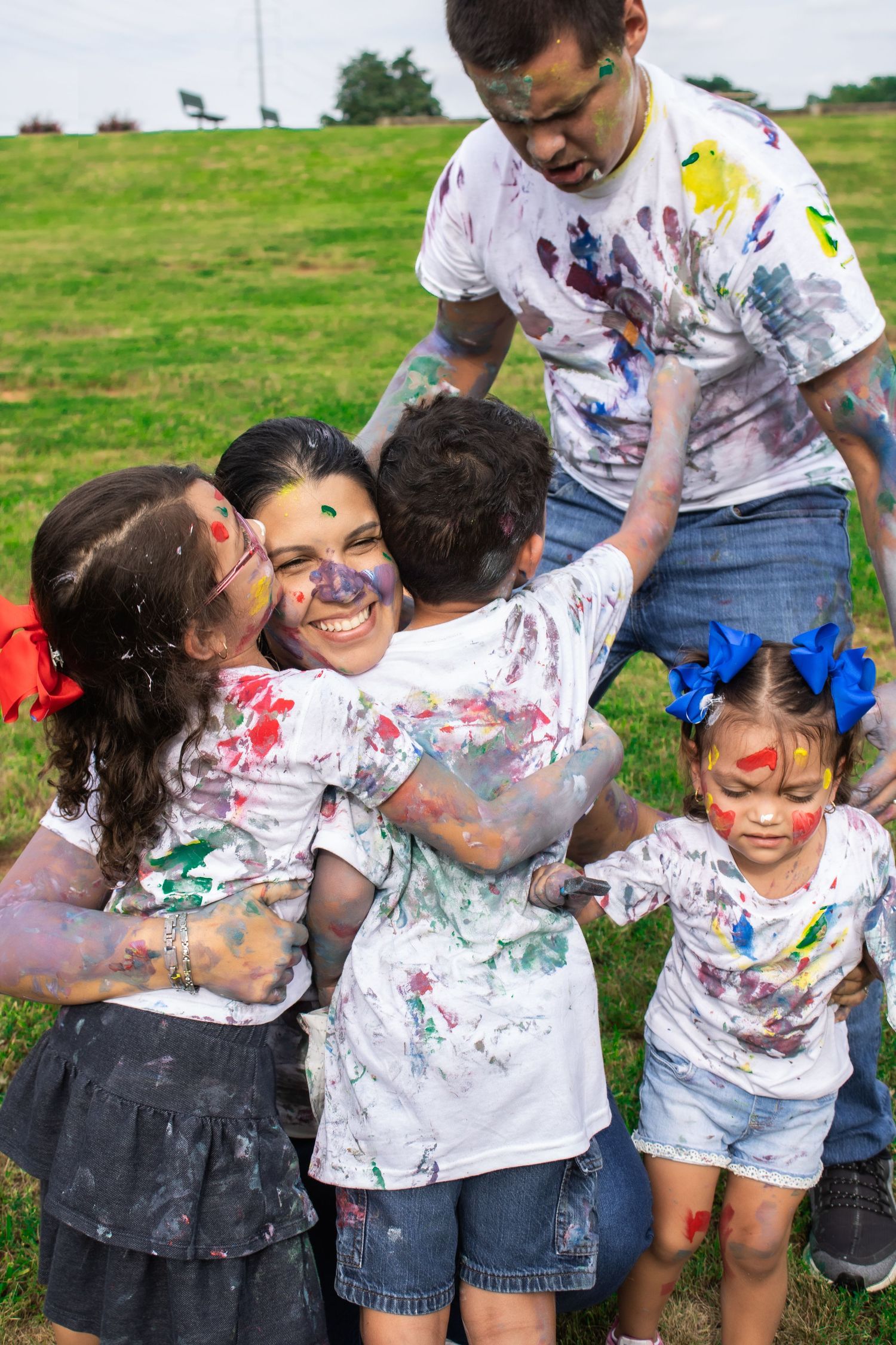 Joyful family covered in paint colors embracing during outdoor activities.