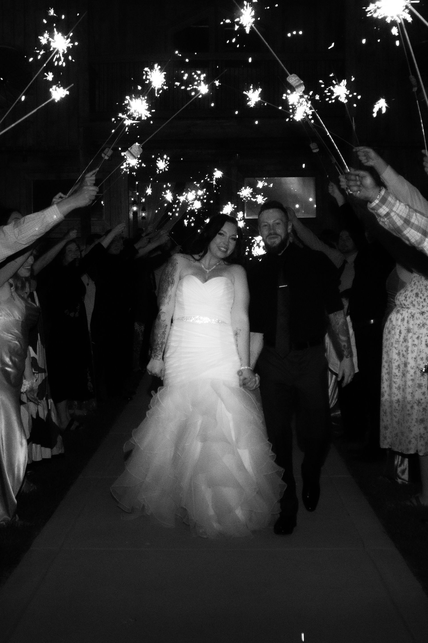 Wedding party dancing with sparklers creating a magical nighttime atmosphere.