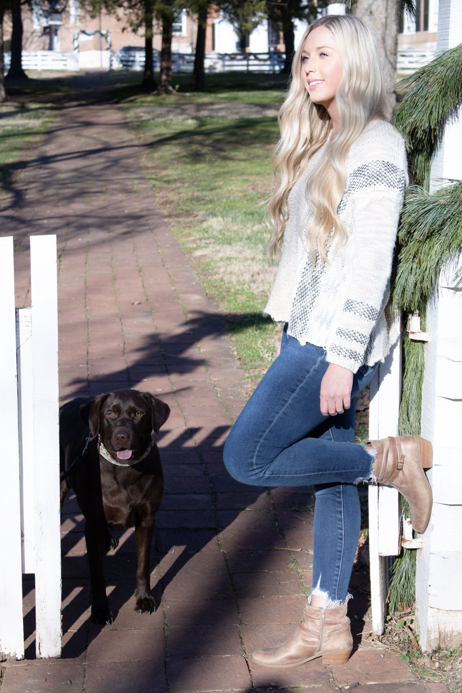 Pet photo session by white picket fence with black dog and casual outdoor styling.